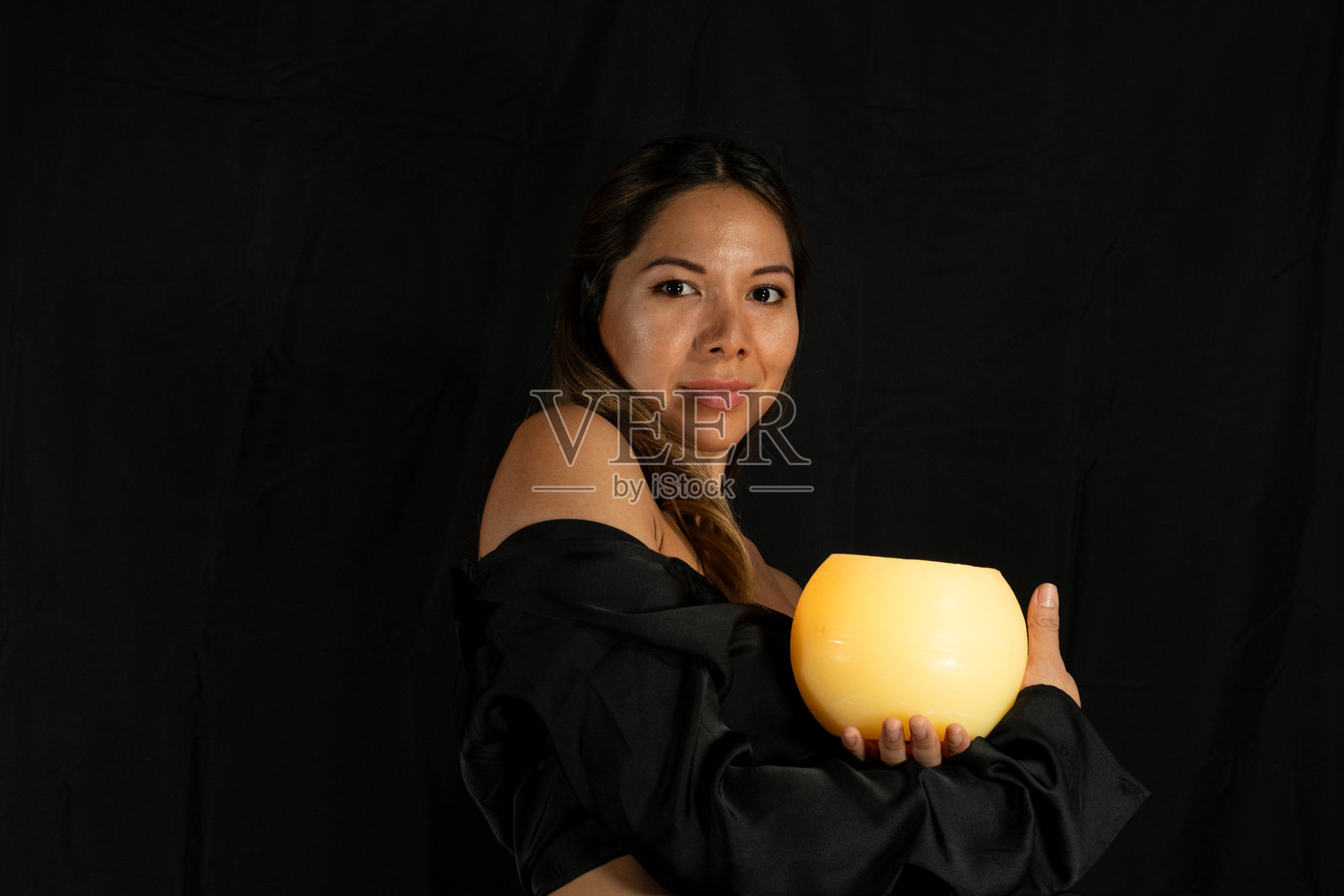 手持蜡烛的拉丁裔女性在黑色背景前摆姿势照片摄影图片