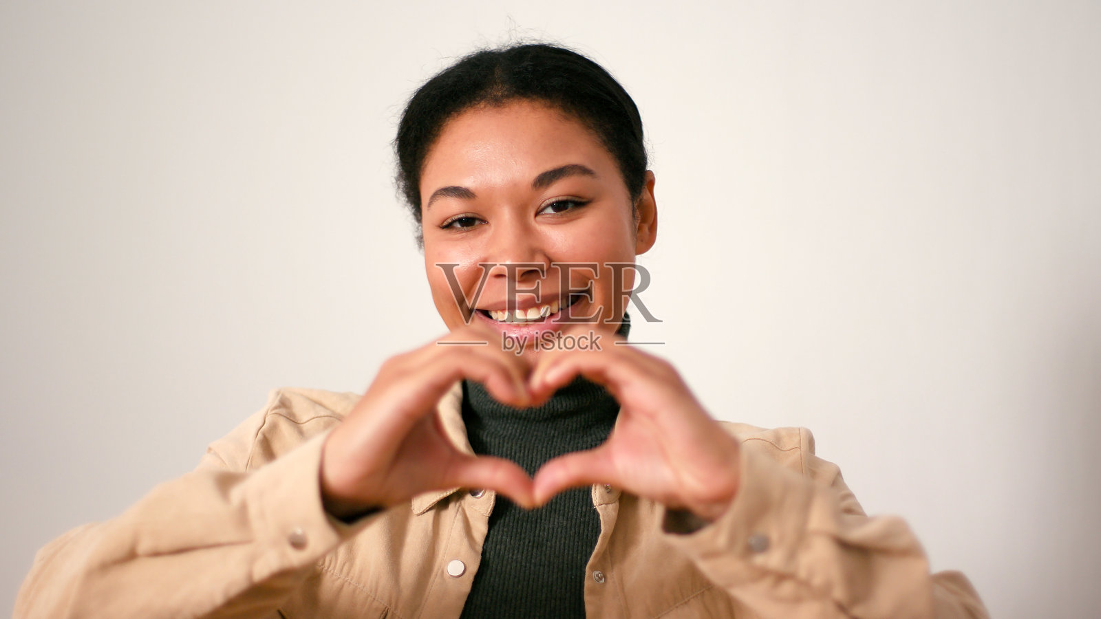 快乐的西班牙裔女性用手指做出心形并送出空气吻照片摄影图片