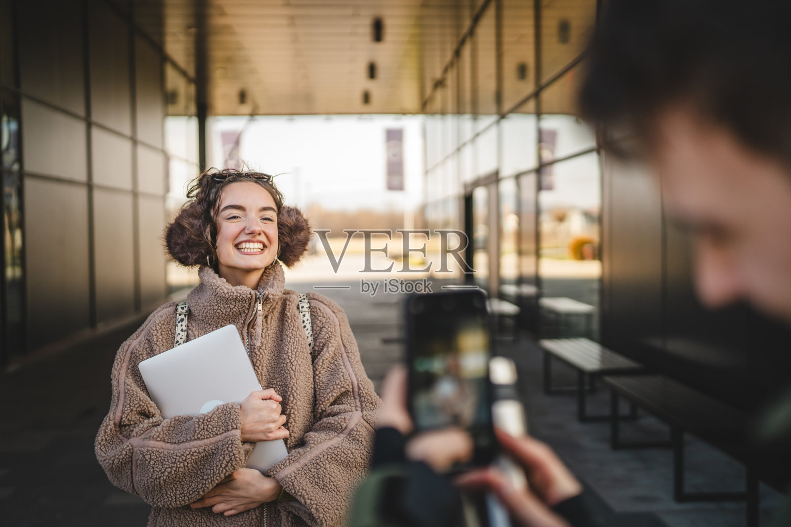 年轻男子在户外用手机拍摄年轻女子的照片照片摄影图片