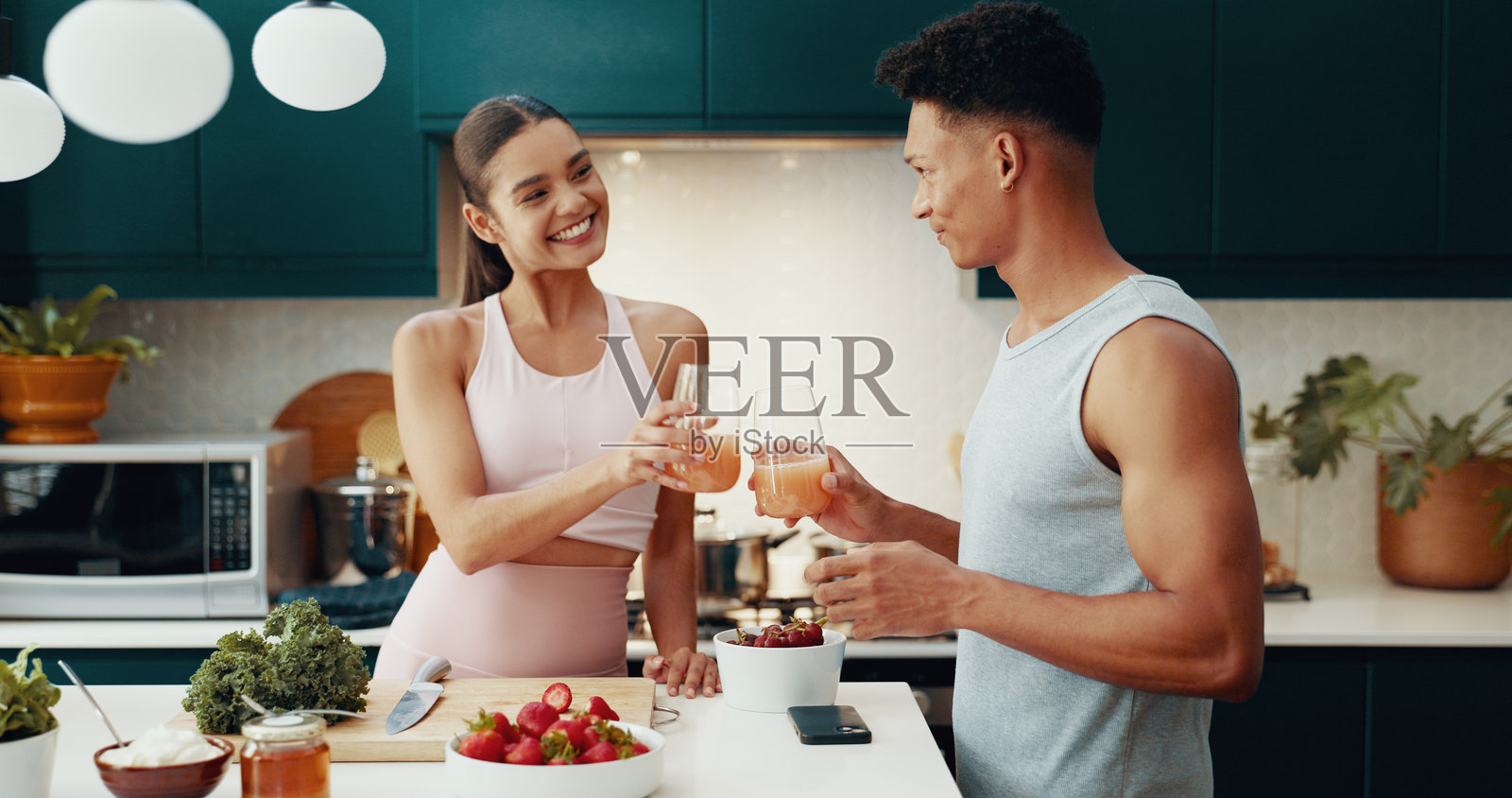 情侣在健康饮食的家中为健身干杯，享用果汁，营养饮食和增进感情。人们为早餐的肠道健康、早晨排毒和素食成分的减肥饮品欢呼。照片摄影图片