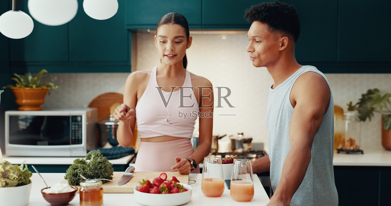 情侣在家中一起烹饪并讲解健康餐食的食谱，增进感情。人们在准备早餐小吃，进行早晨排毒和减肥的交流。照片摄影图片
