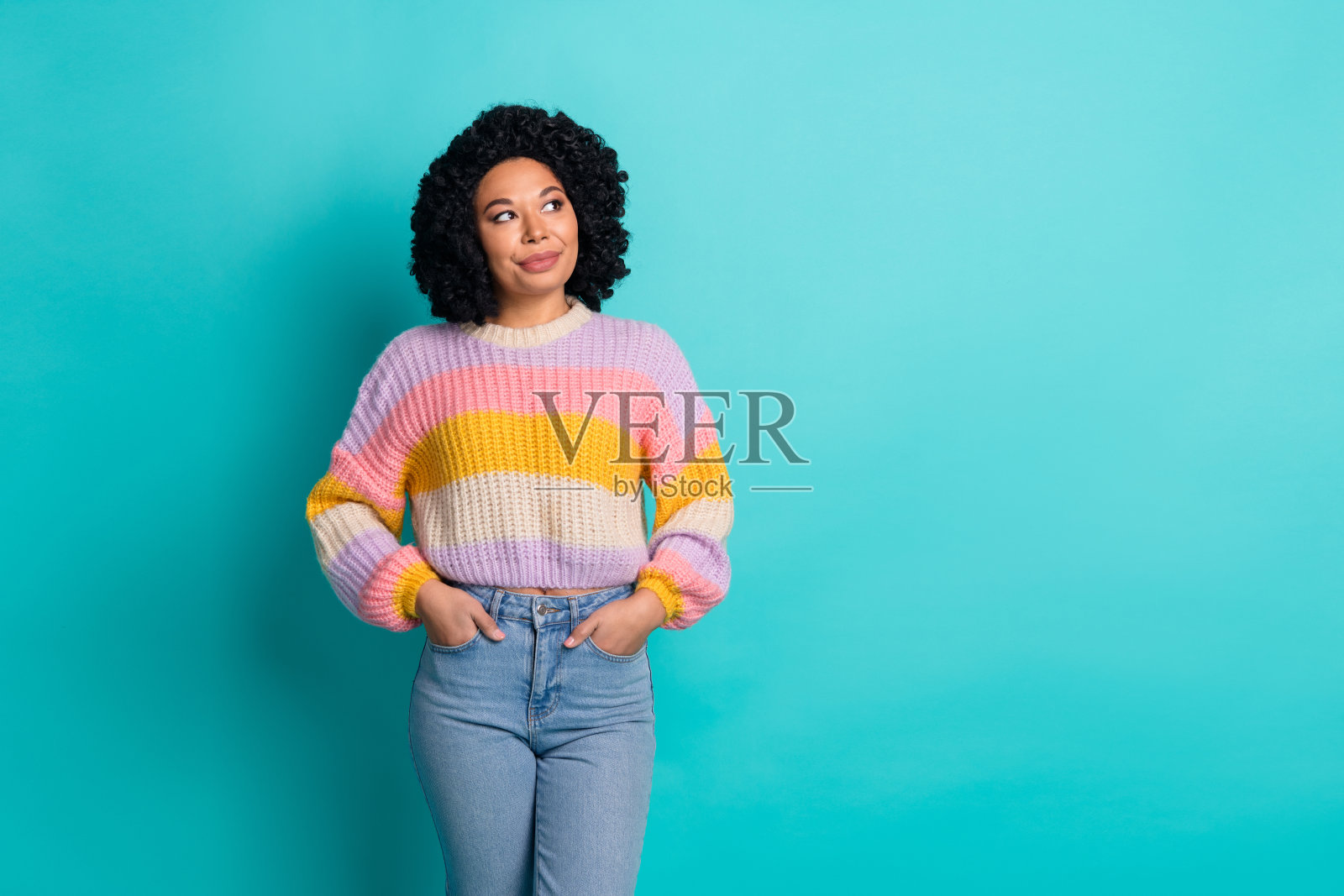 微笑的年轻女性穿着时尚的彩色毛衣，背景是生动的青绿色。照片摄影图片