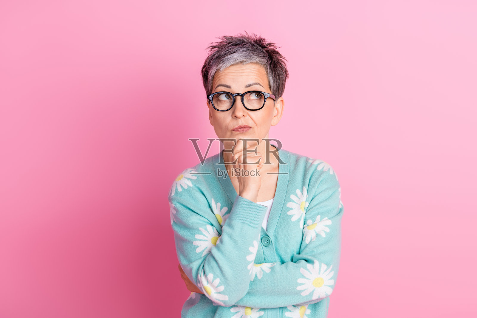 时尚女性在粉色背景前思考，穿着春季开衫。照片摄影图片