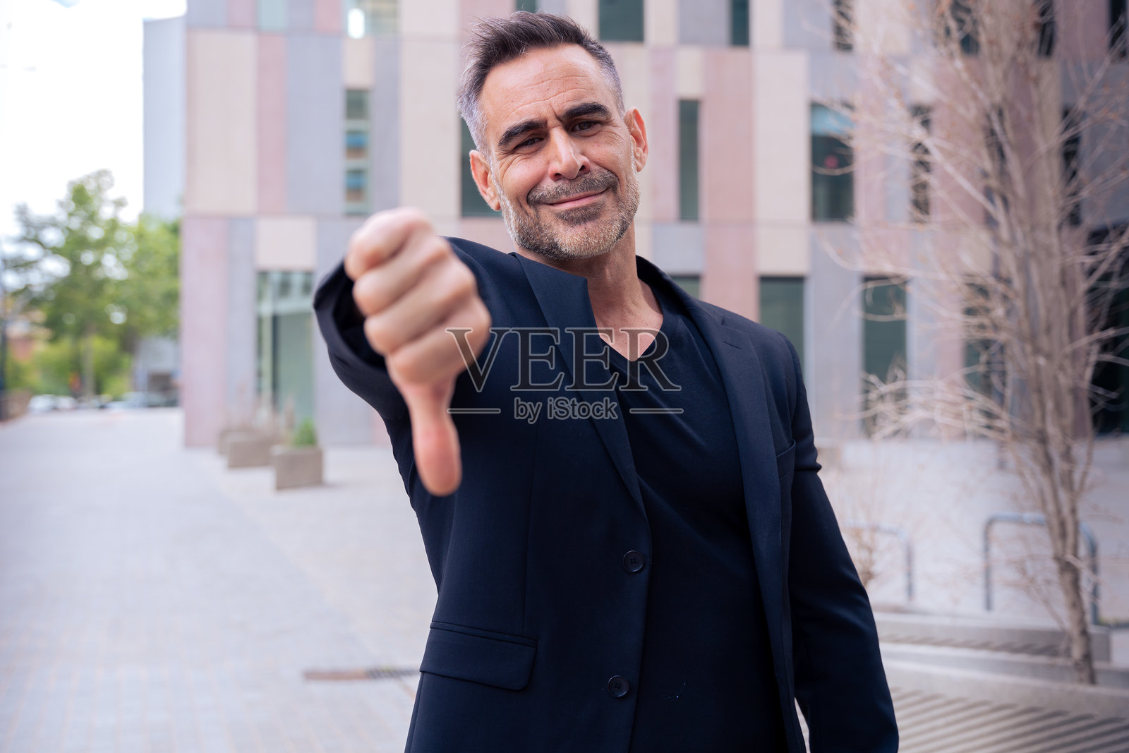 商务人士在户外用拇指向下指着，惊讶地看着镜头照片摄影图片