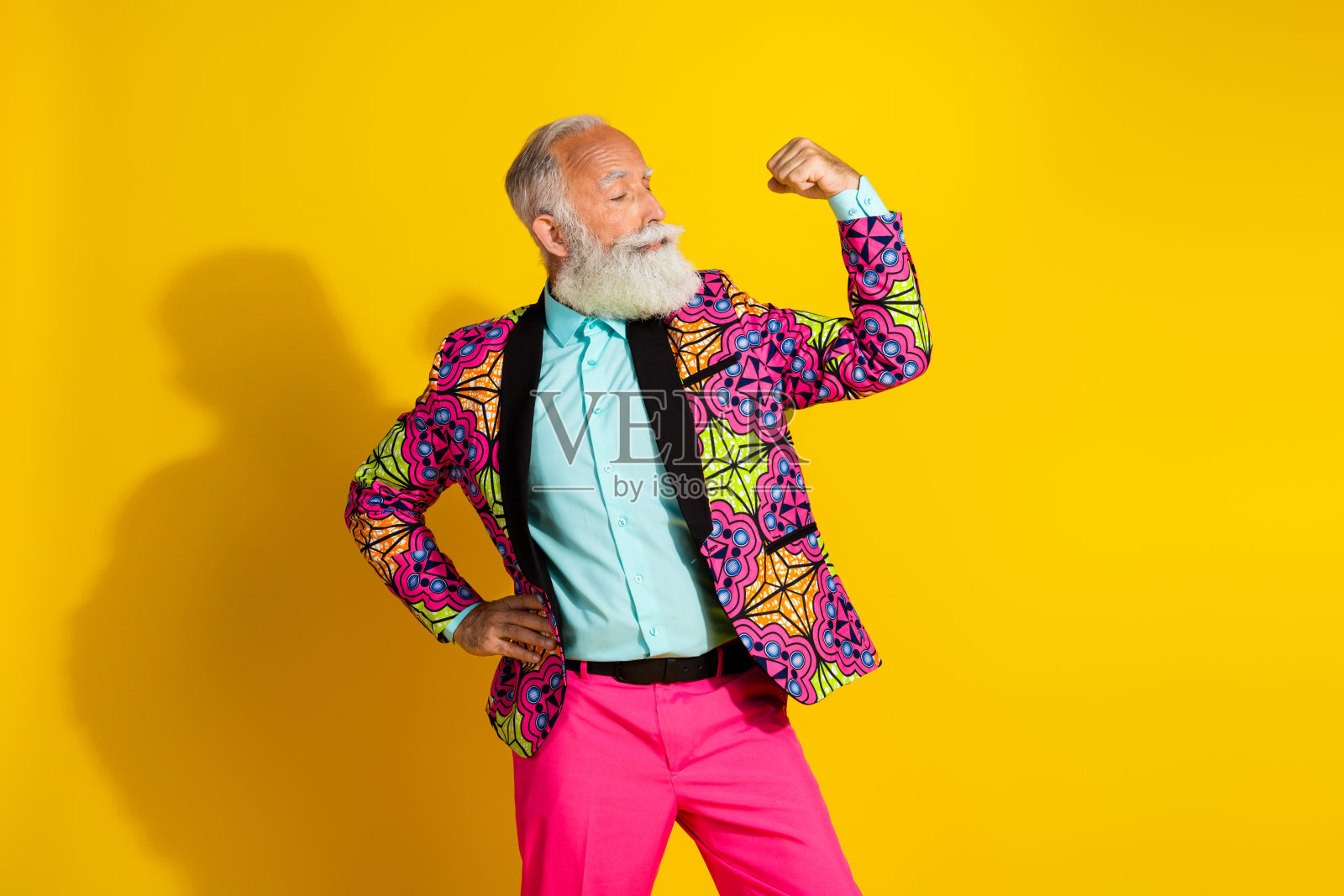 身穿时尚亮丽西装的男士在黄色背景下展示肌肉。照片摄影图片