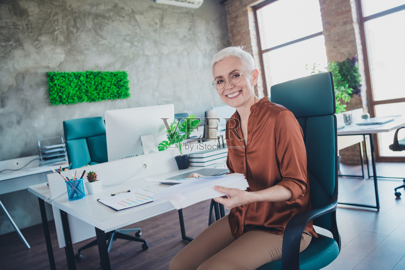 专业女性企业领导坐在桌前工作简历，穿着棕色衬衫，在明亮舒适的办公室内共事。照片摄影图片