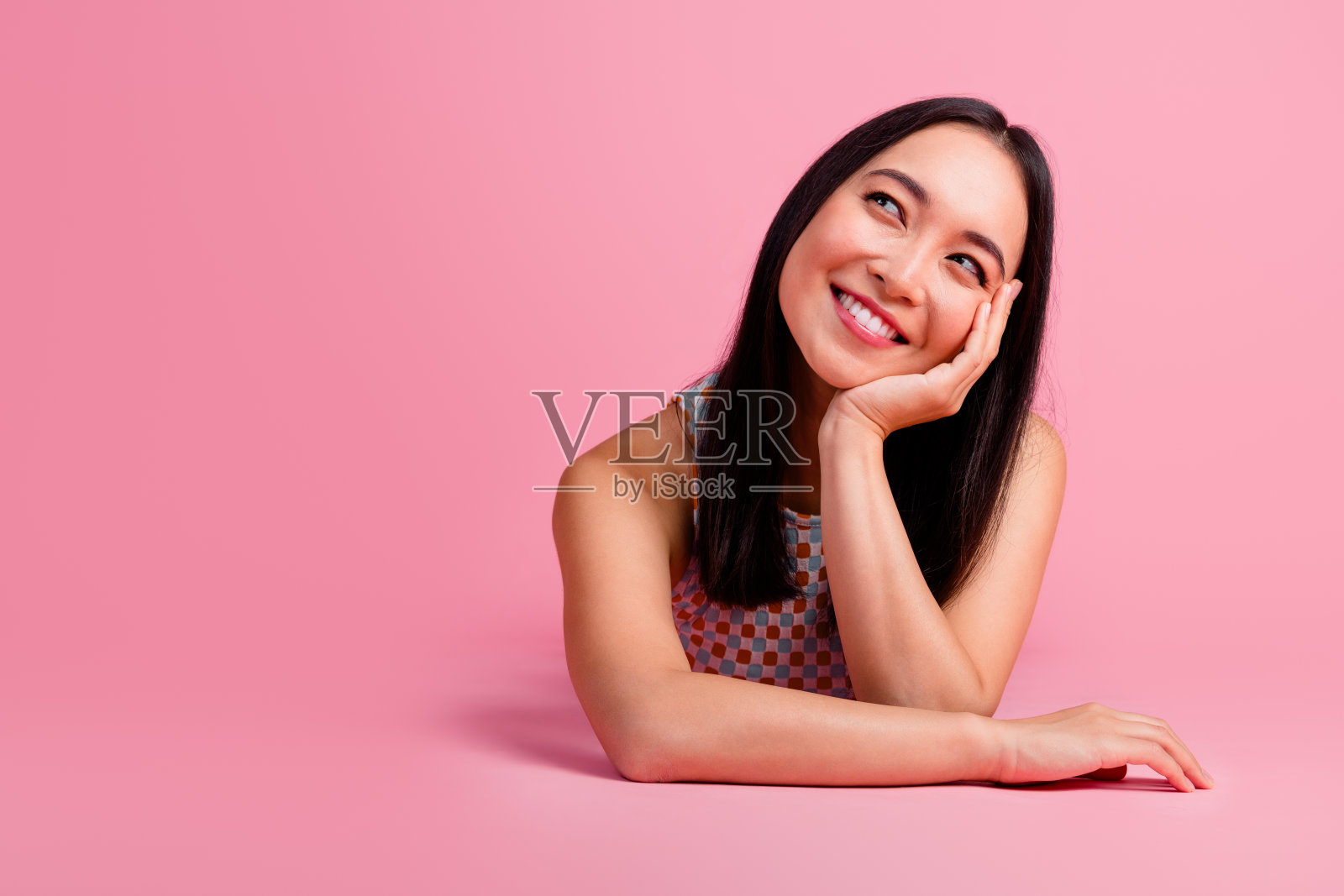 迷人的年轻女性穿着时尚的夏季服装，在粉色背景前微笑，展现出快乐的情绪。照片摄影图片