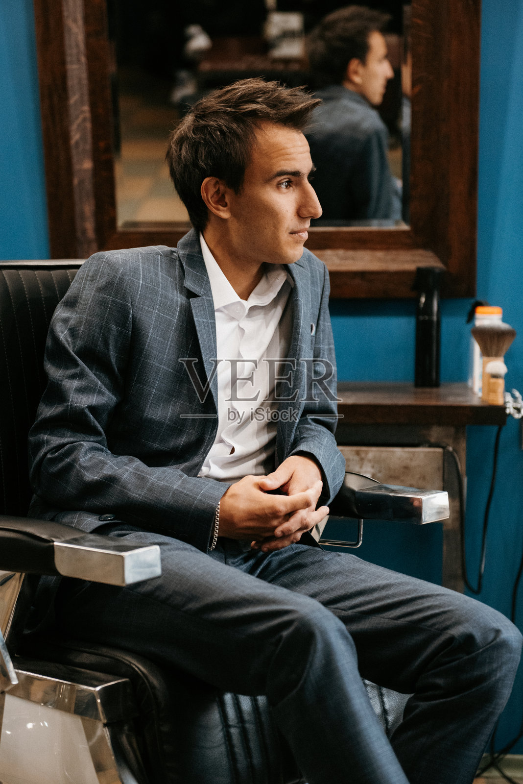 穿着灰色格子西装的年轻人在理发店内照片摄影图片