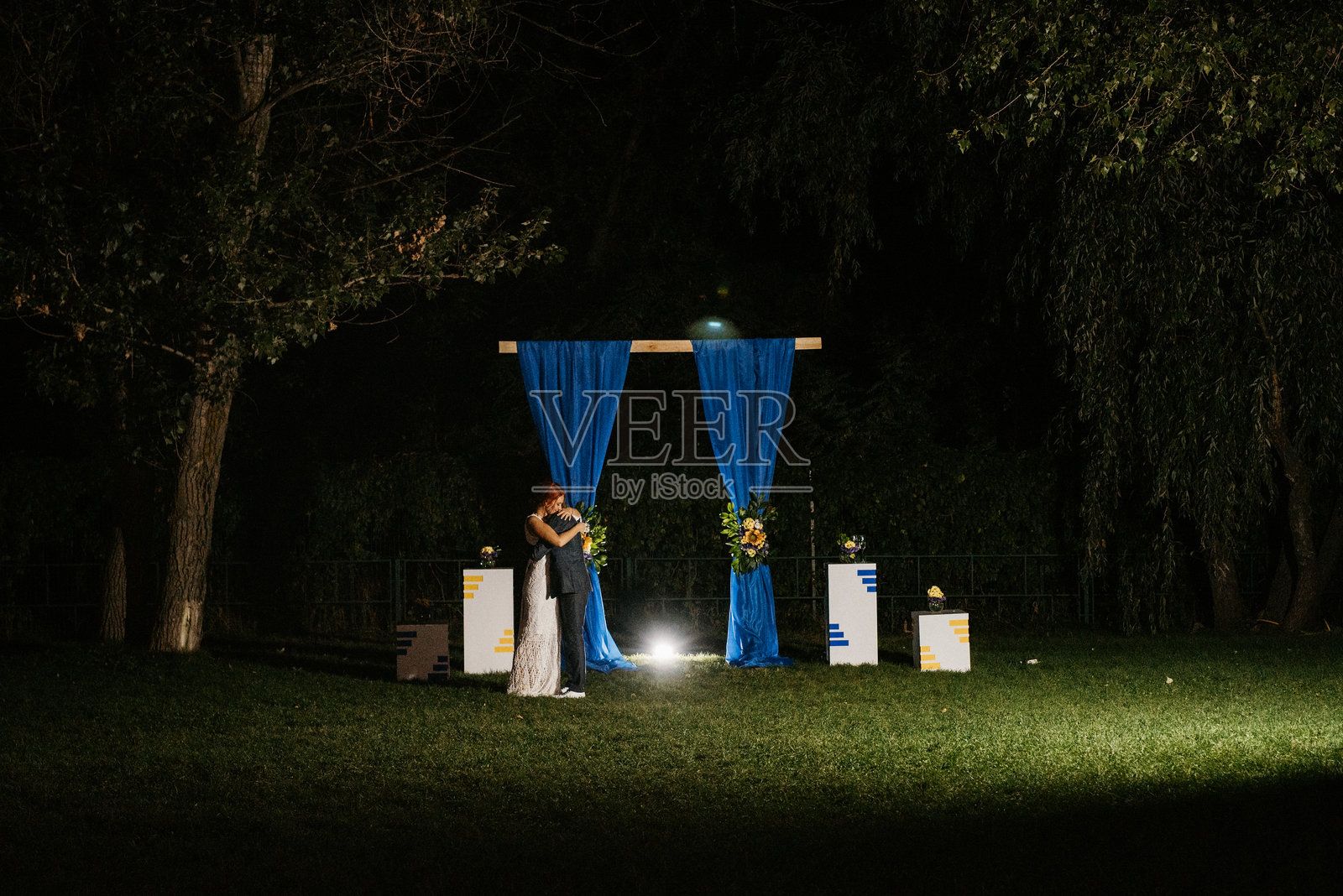 年轻情侣在婚礼拱门的背景下切蛋糕照片摄影图片