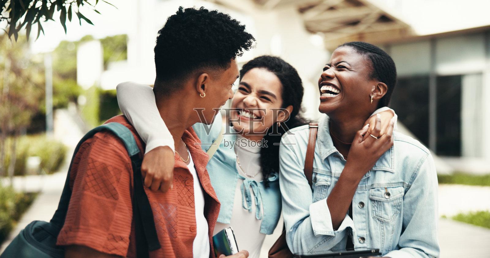 大学生们在校园里一起欢笑，分享有趣的笑话、漫画故事和增进友谊。教育、人与幽默在大学学习间隙中，奖学金和学习支持的户外活动。照片摄影图片