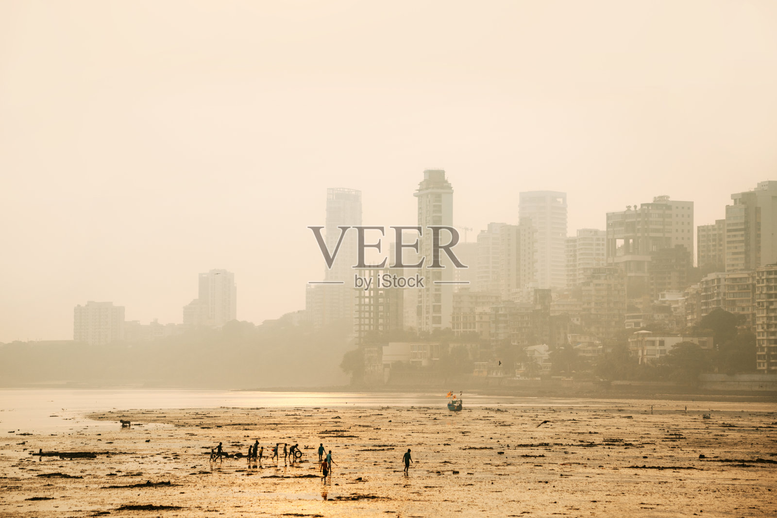 孟买城市景观上空的金色光芒与沙滩上的人们照片摄影图片