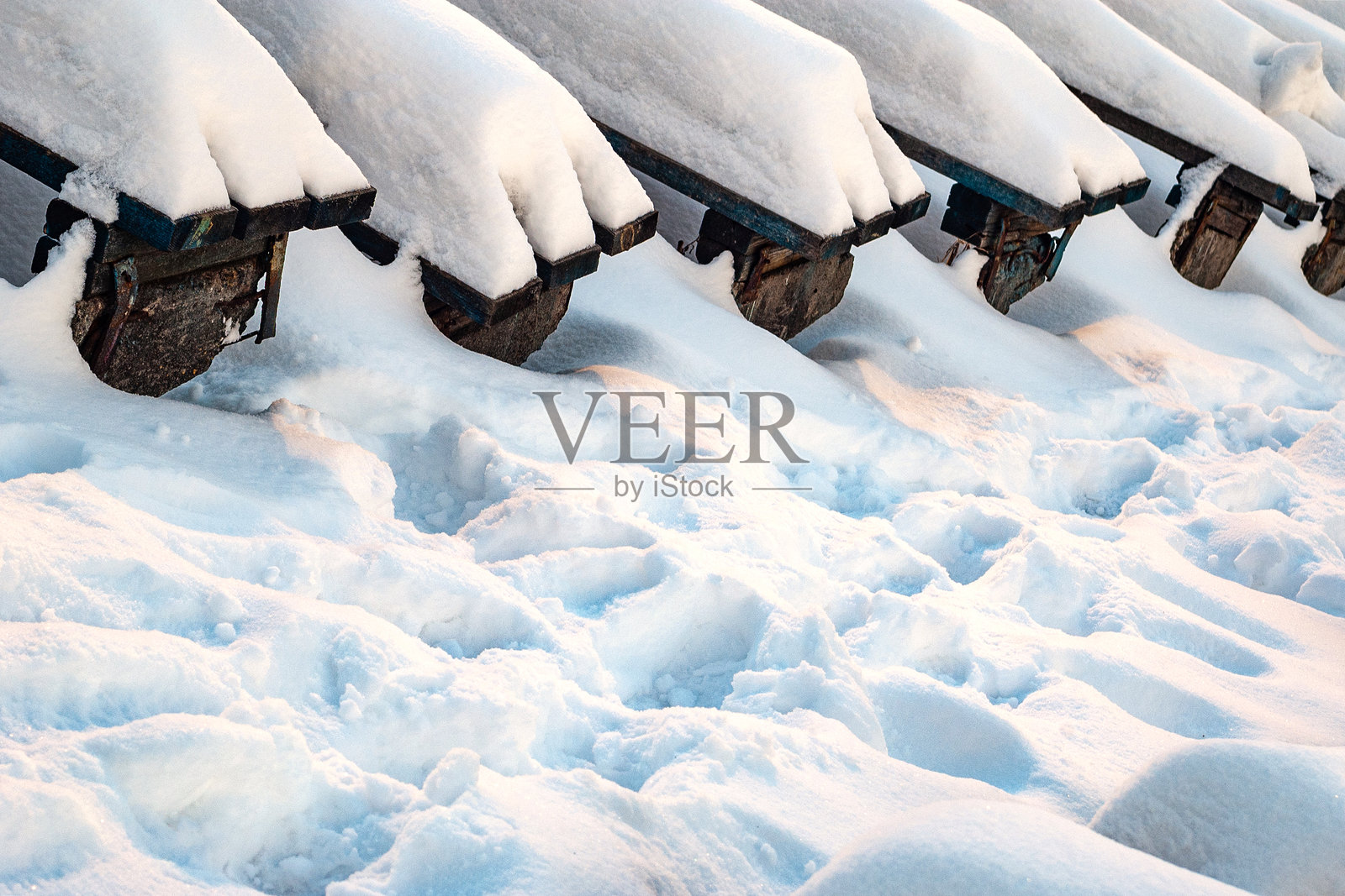 被雪覆盖的老体育场长椅。冬季大雪过后的体育场看台。照片摄影图片