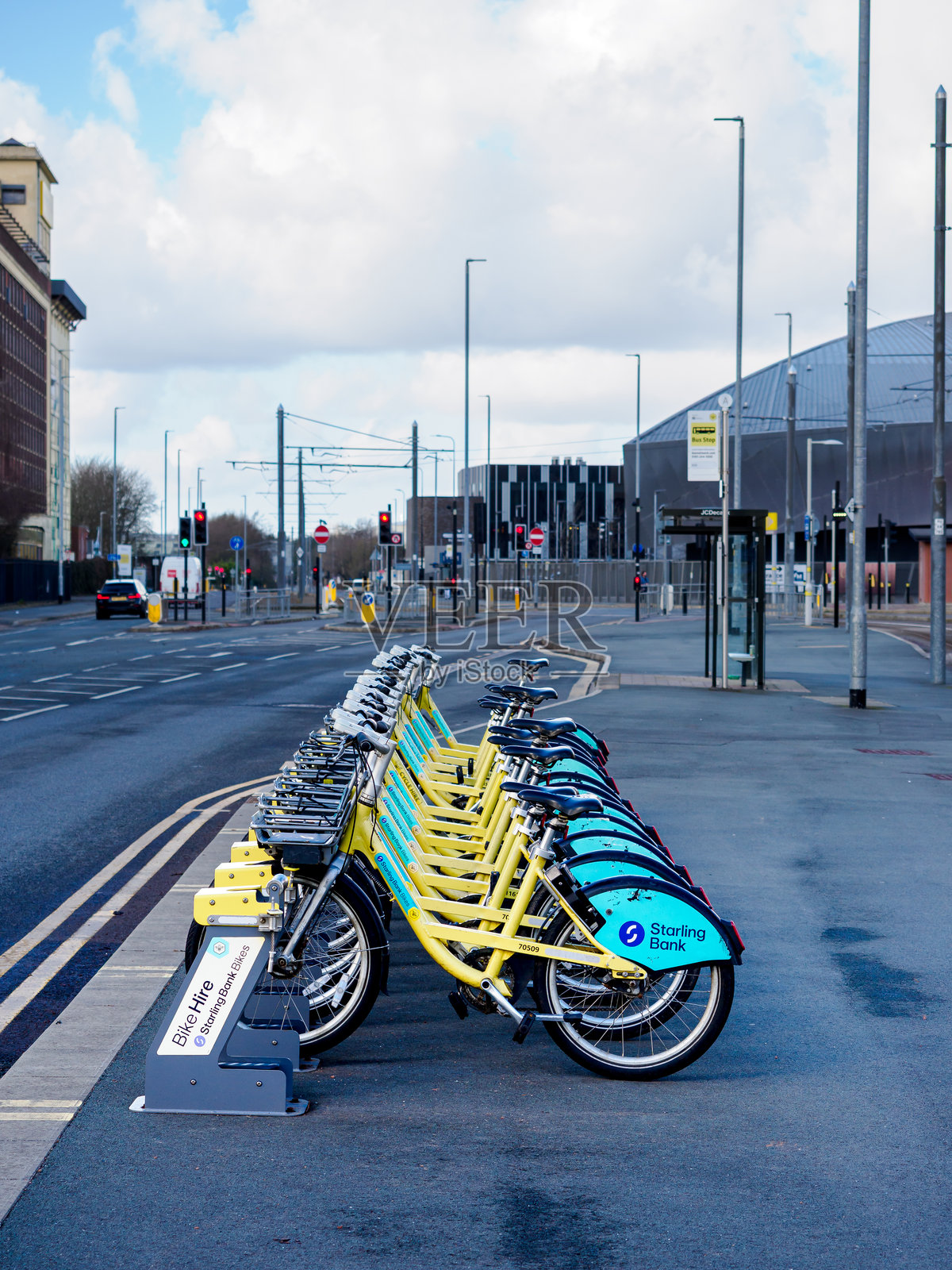 五颜六色的租赁自行车在阴云密布的城市街道上整齐排列。照片摄影图片
