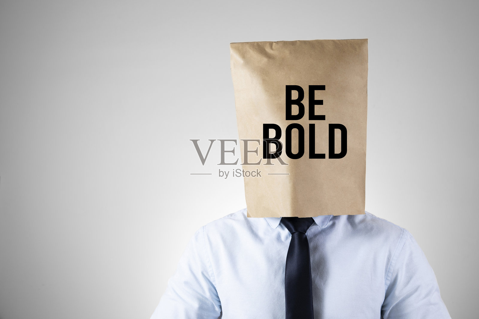 头上戴着纸袋的商人，旁边有“勇敢做自己”的便条照片摄影图片