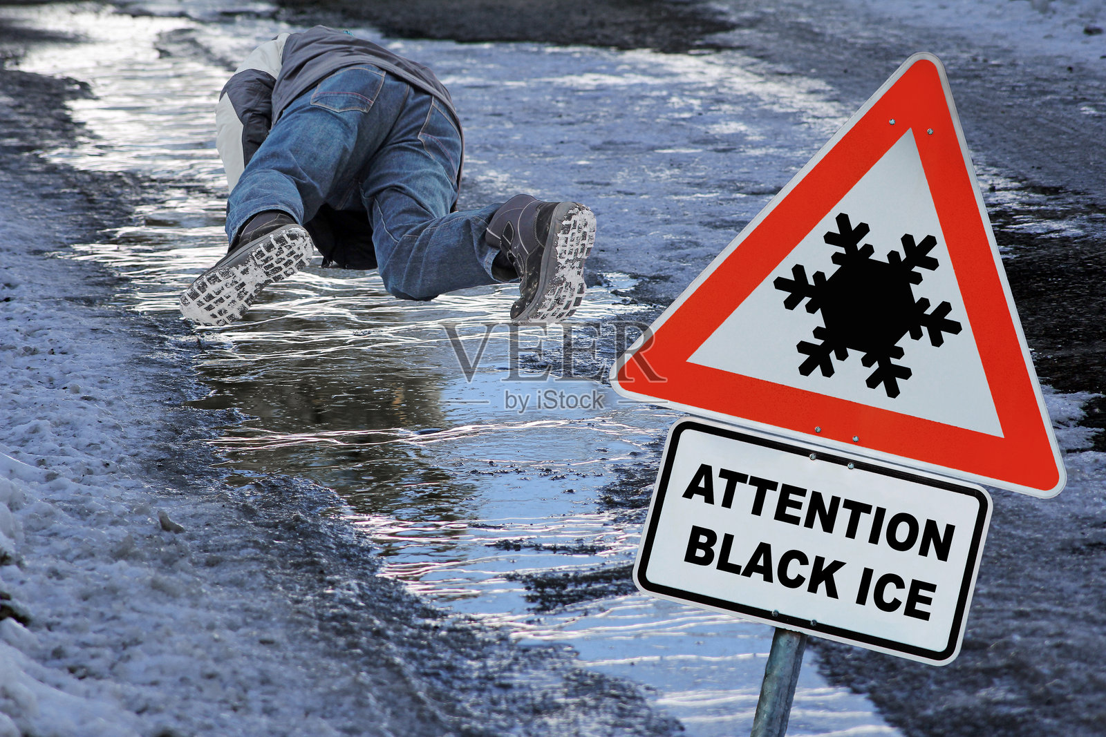 冬季人行道上有警示标志，提醒注意黑冰。一名男子在黑冰上滑倒。照片摄影图片