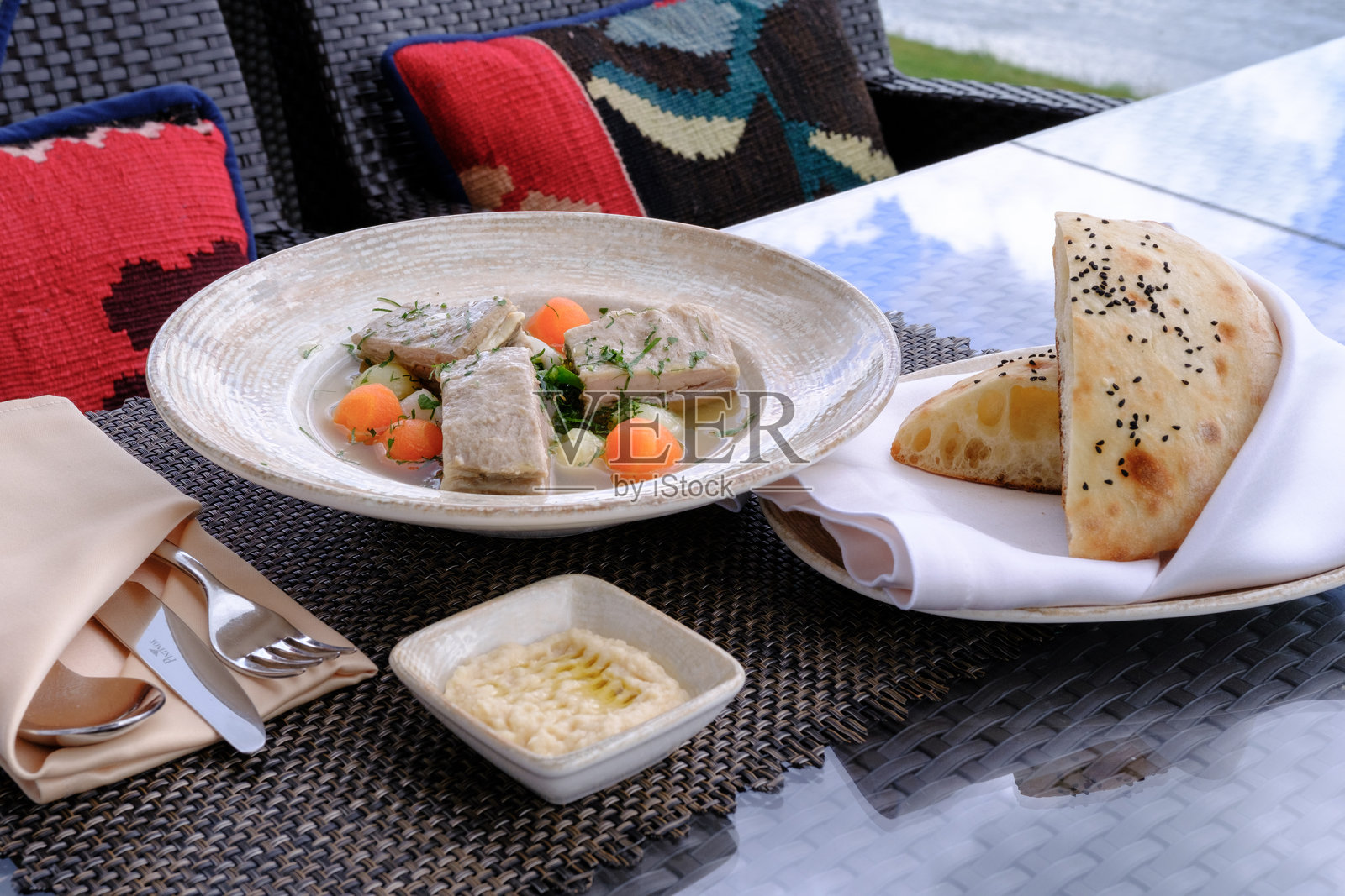 看起来美味的炖菜，里面有鱼肉块，配有扁面包和一旁的调味酱。照片摄影图片