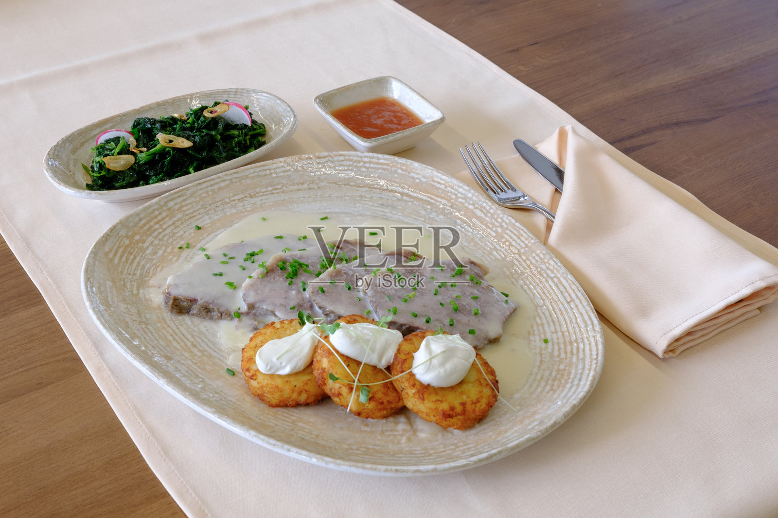 奶油酱汁中的美味切片肉，配以土豆饼和菠菜照片摄影图片