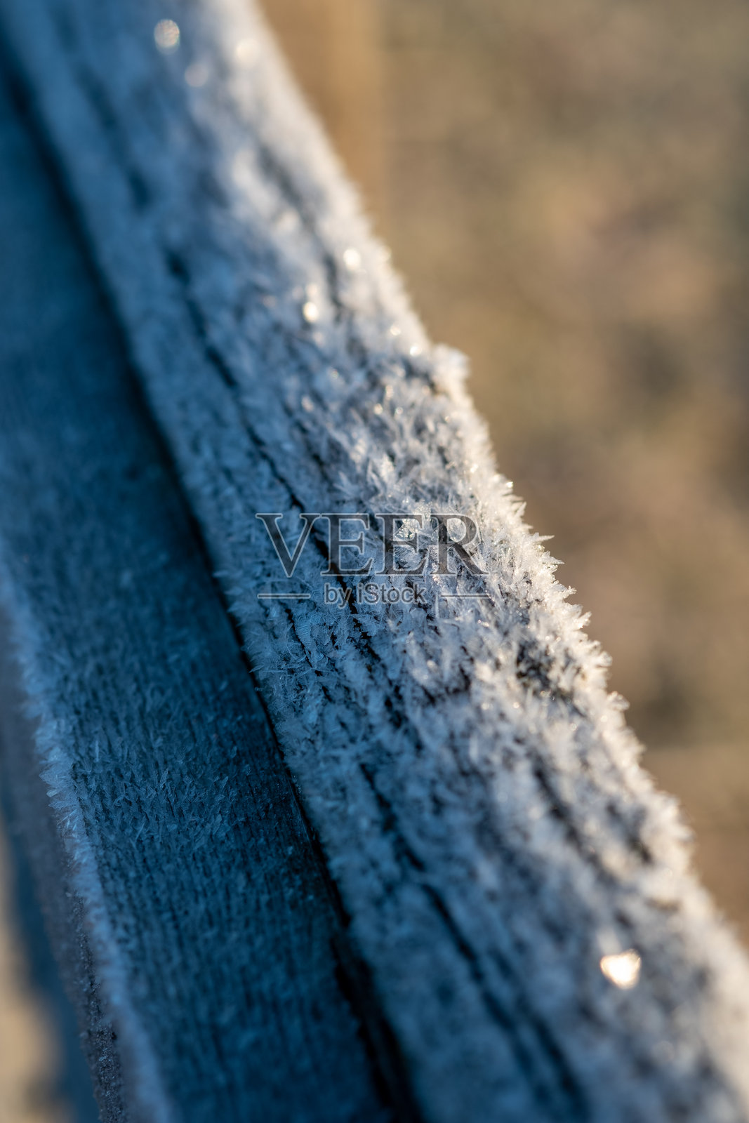 霜晶体精致地附着在风化的木柱上，捕捉着晨光。照片摄影图片