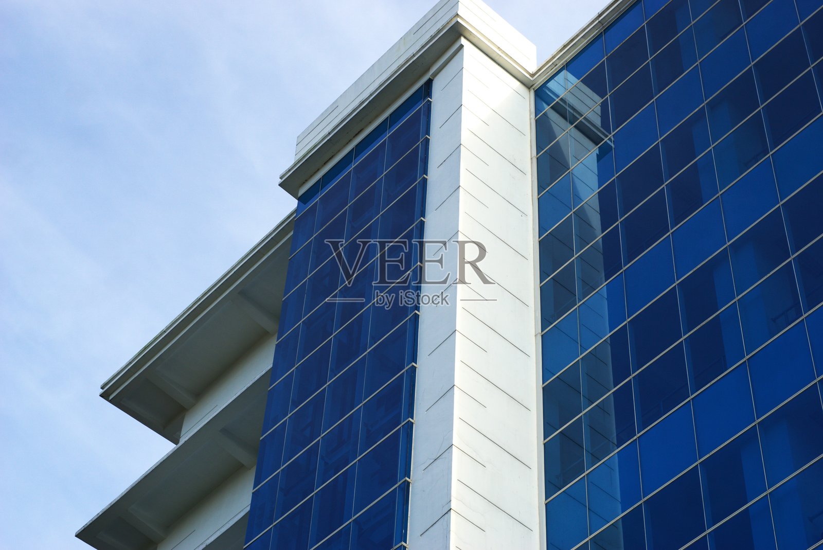 现代办公大楼的低角度视图，蓝色玻璃窗立面和白色墙壁照片摄影图片