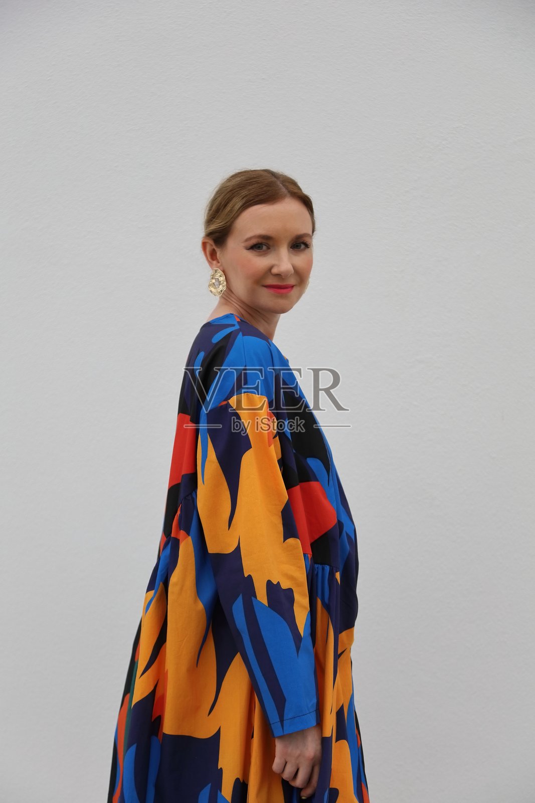 穿着色彩斑斓长裙的美丽年轻女性站在建筑前照片摄影图片