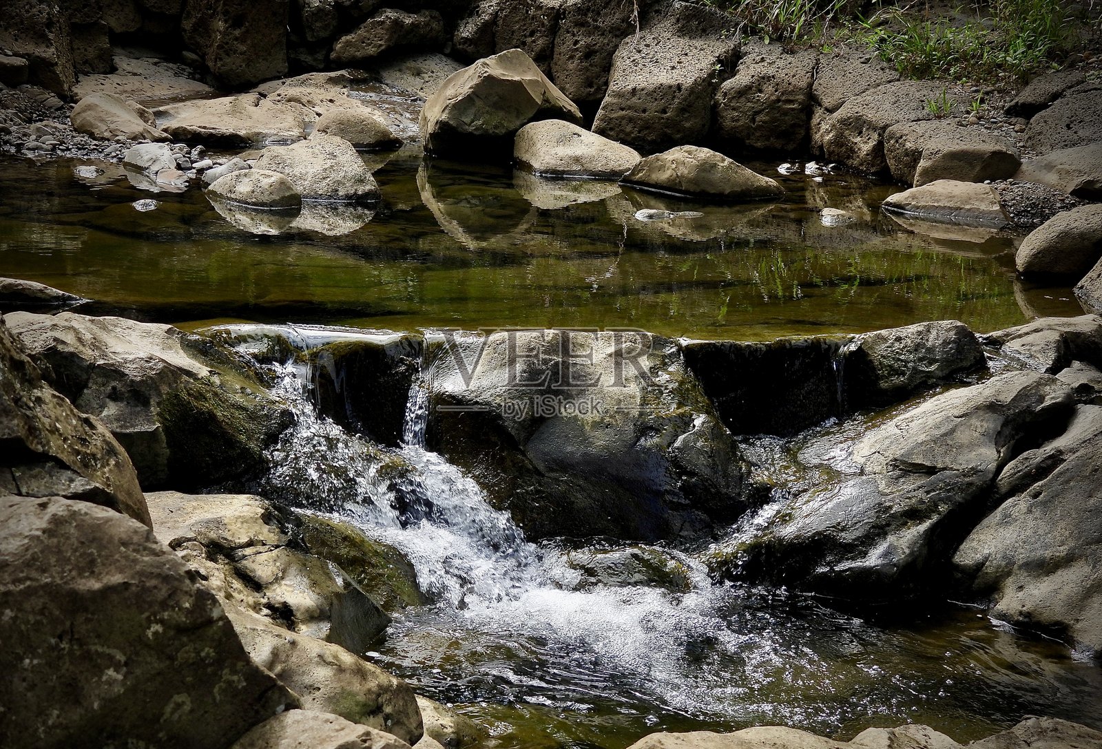 清澈的霍拉瓦努伊溪水在北毛伊县的霍拉瓦谷中流淌，流经光滑的岩石形成瀑布。照片摄影图片