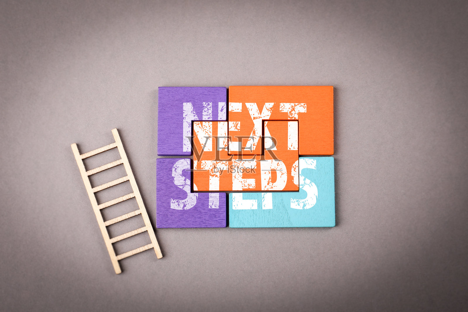 下一步。灰色背景上的彩色木质拼图照片摄影图片