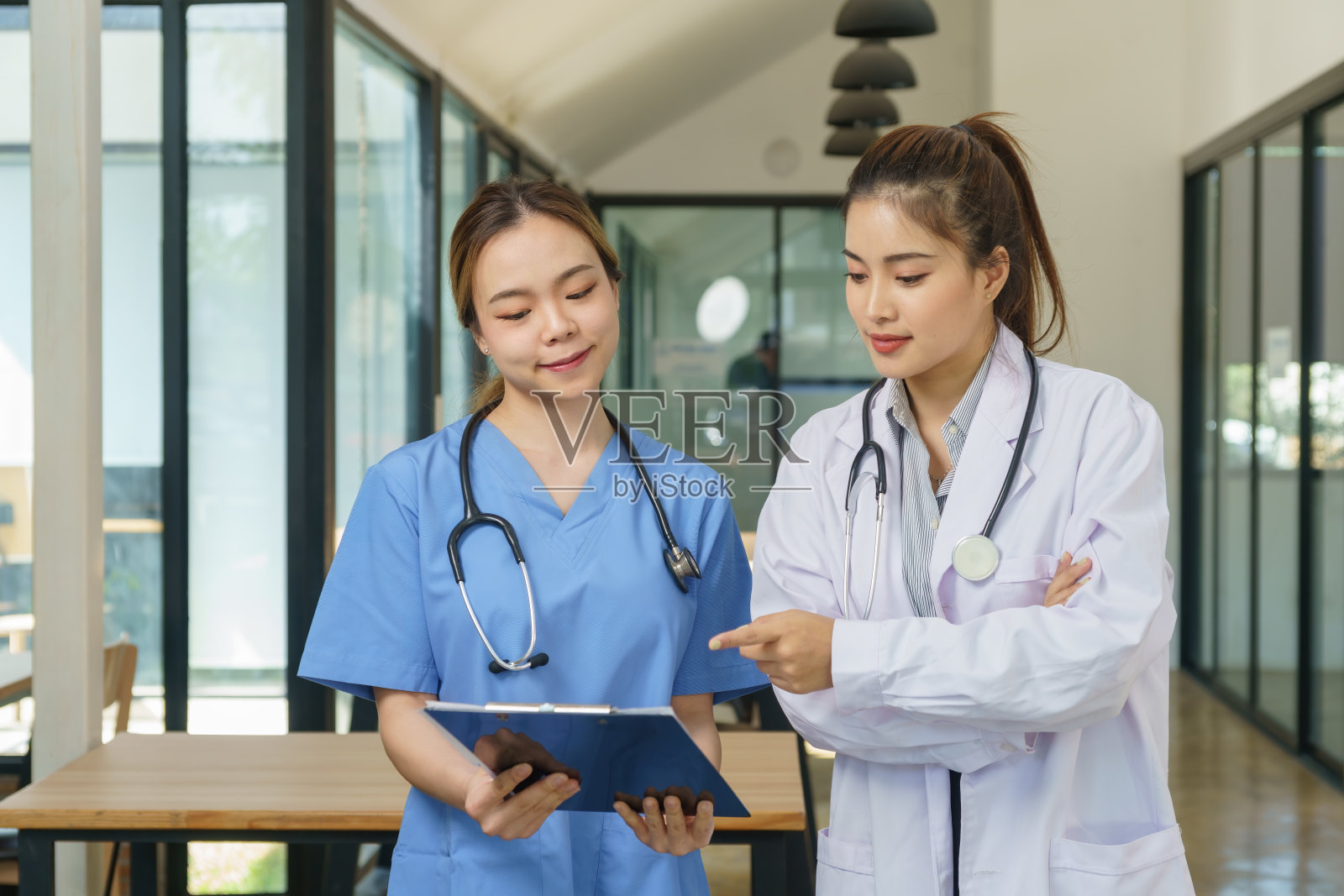 女性医疗专业人员聚在一起讨论病历。照片摄影图片