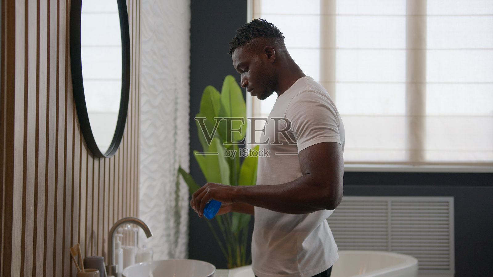 非裔美国男性在浴室使用牙齿清洁产品漱口，进行口腔卫生护理，漱口抗菌漱口水，保持清新口气，早晨日常护理。照片摄影图片