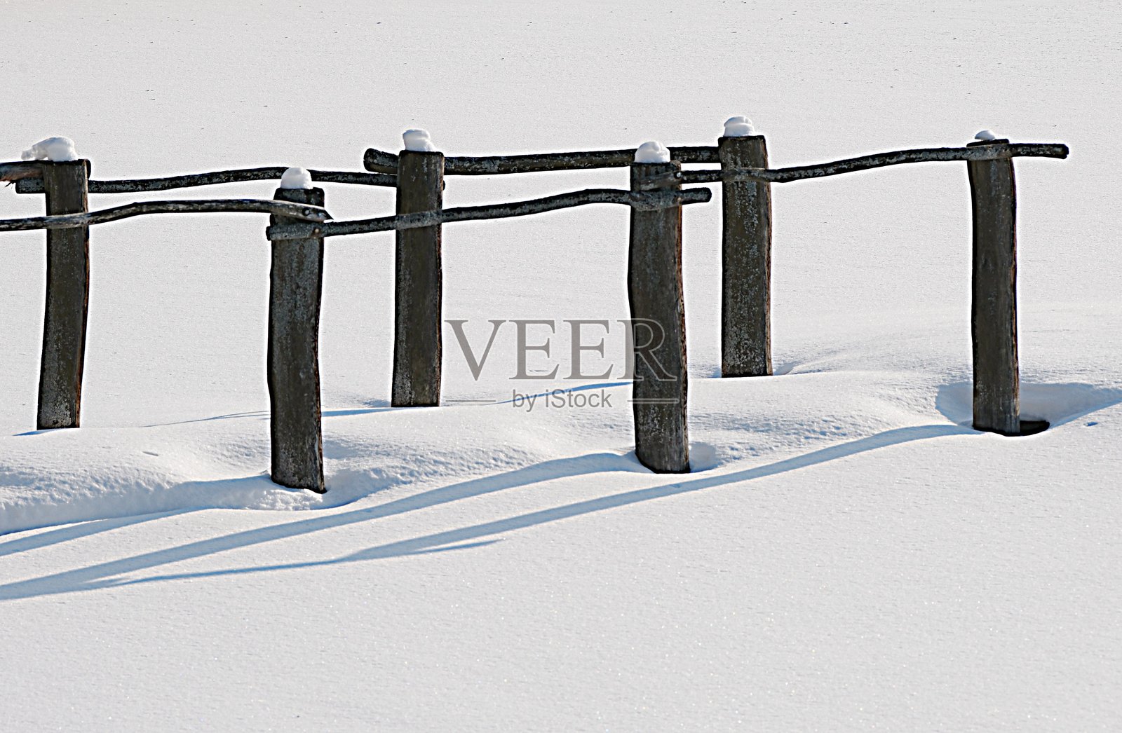 雪覆盖的桥梁木柱横跨冰冻的池塘。冬季天气照片摄影图片