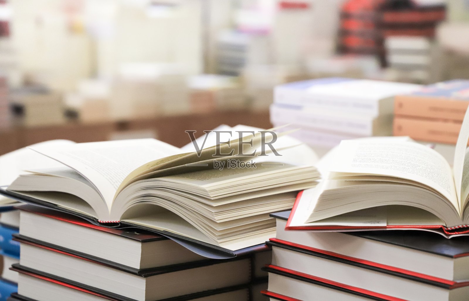 桌子上的一叠书。一本打开的书。照片摄影图片