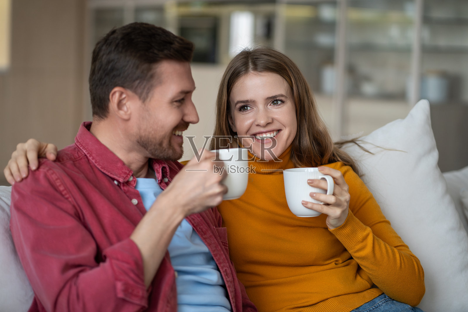 恩爱情侣在家沙发上懒洋洋地度过周末，喝着咖啡，享受交谈。照片摄影图片