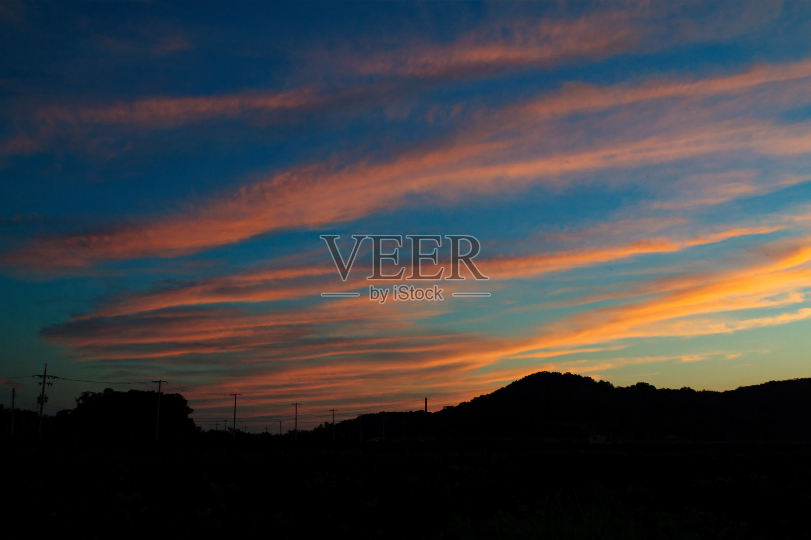 日落时分，红色的云彩与黑暗中的乡村田野。照片摄影图片