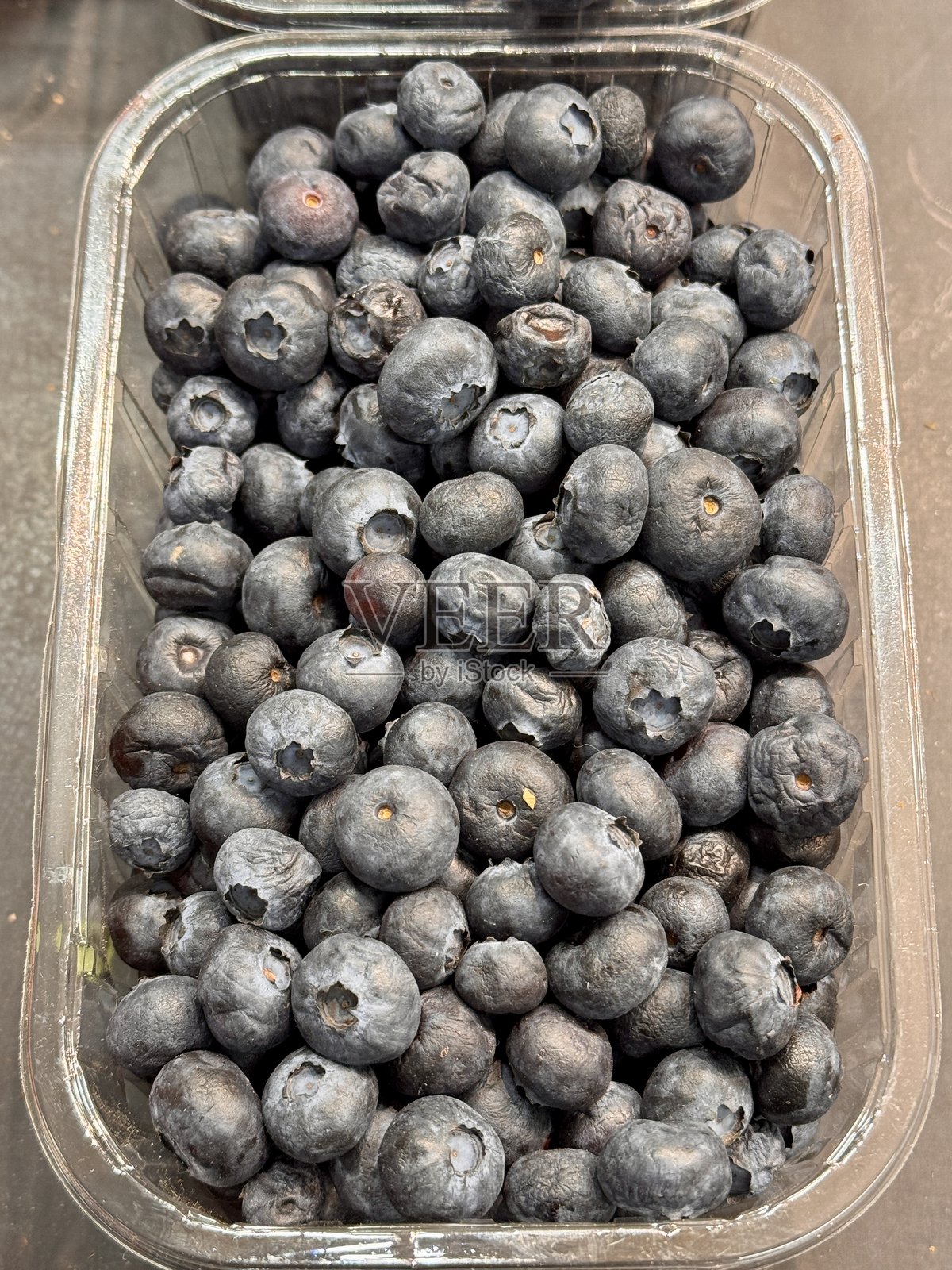 超市柜台上透明容器中的新鲜黑蓝莓待售。美味成熟的浆果，适合健康饮食。特写镜头。照片摄影图片