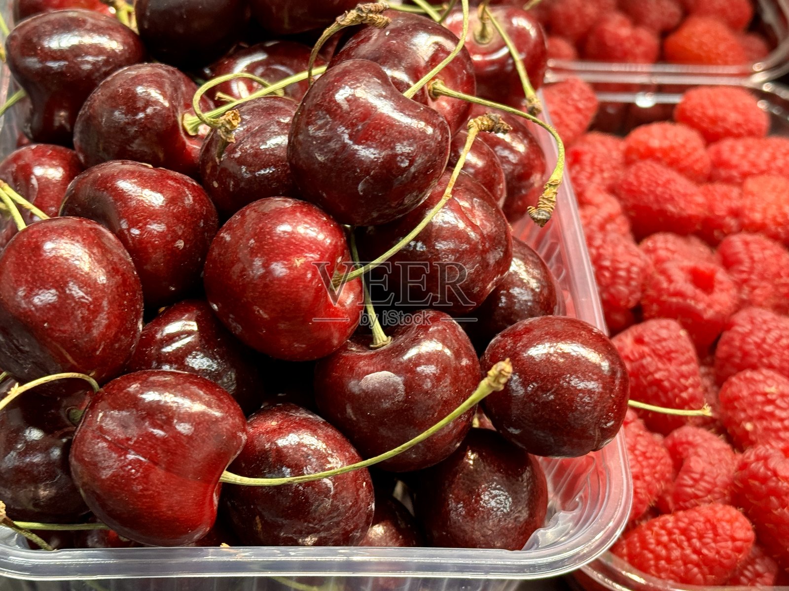新鲜红色成熟樱桃在超市柜台的透明容器中出售。美味的成熟浆果，适合健康饮食。特写镜头照片摄影图片