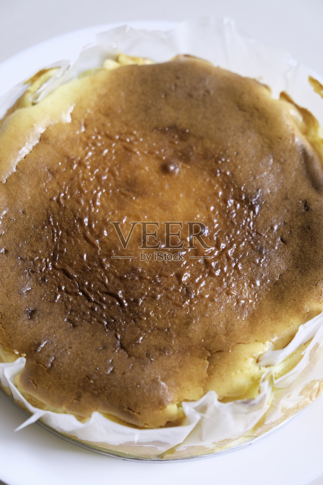 自制巴斯克焦 burnt cheesecake 的特写，放在白色盘子上。照片摄影图片