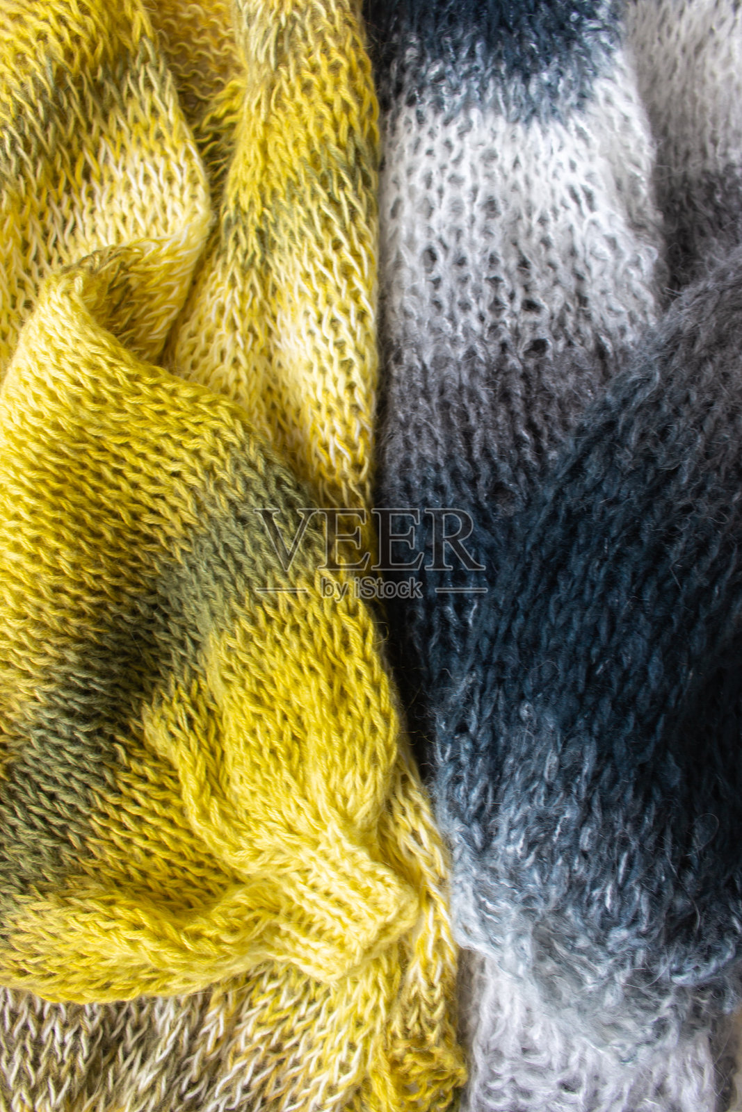 渐变色彩的针织毛衣。黄色和灰色羊毛纱线开衫。针织图案背景。针织生活方式。舒适的爱好。温暖的针织服饰。照片摄影图片