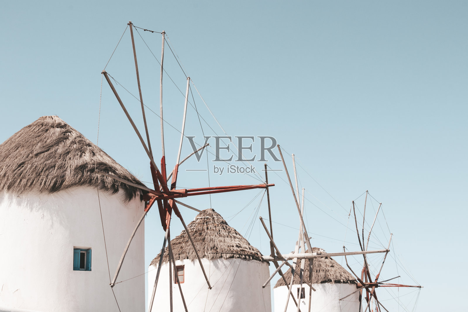 希腊米科诺斯岛上阳光明媚的清空下，三座海滨风车的低角度视图照片摄影图片