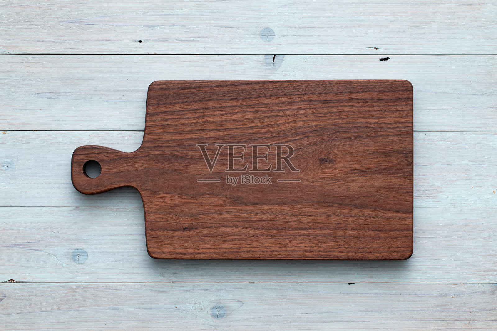 手工制作的胡桃木砧板放在浅蓝色的木桌上。木制砧板放在木质背景上。照片摄影图片