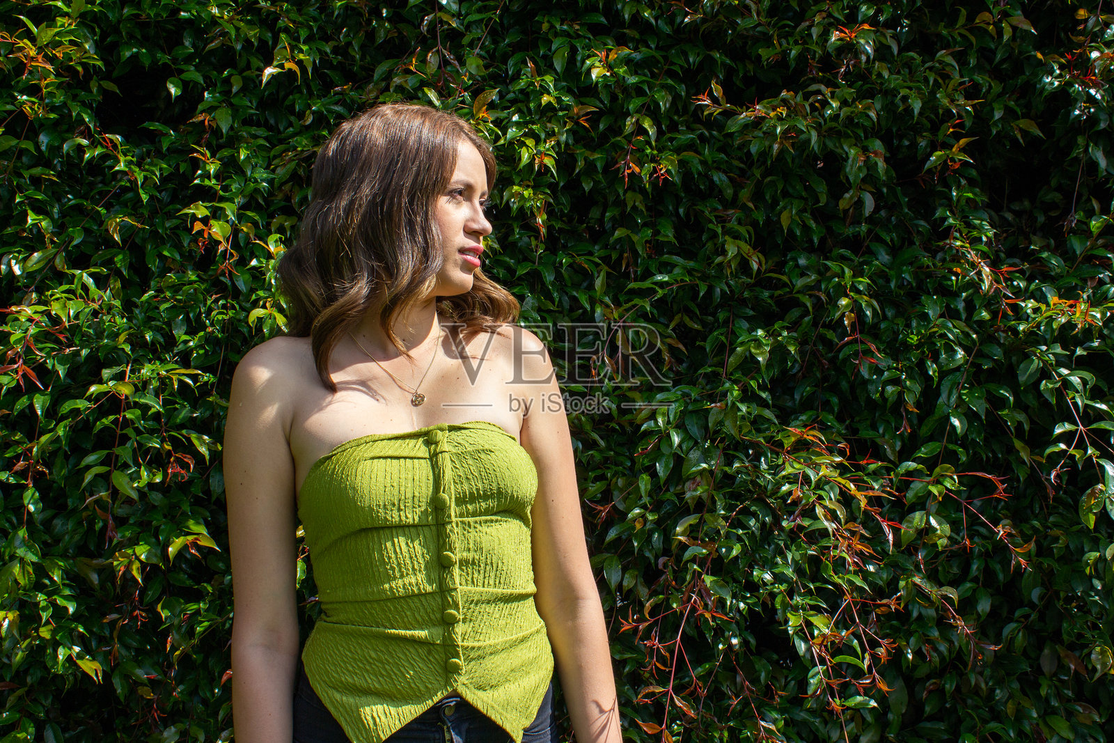 美丽的女性在一面叶子墙前展示模特风采照片摄影图片