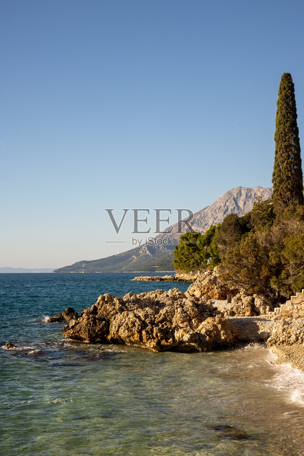 宁静的海岸景观，岩石海岸线与山脉相映成趣照片摄影图片
