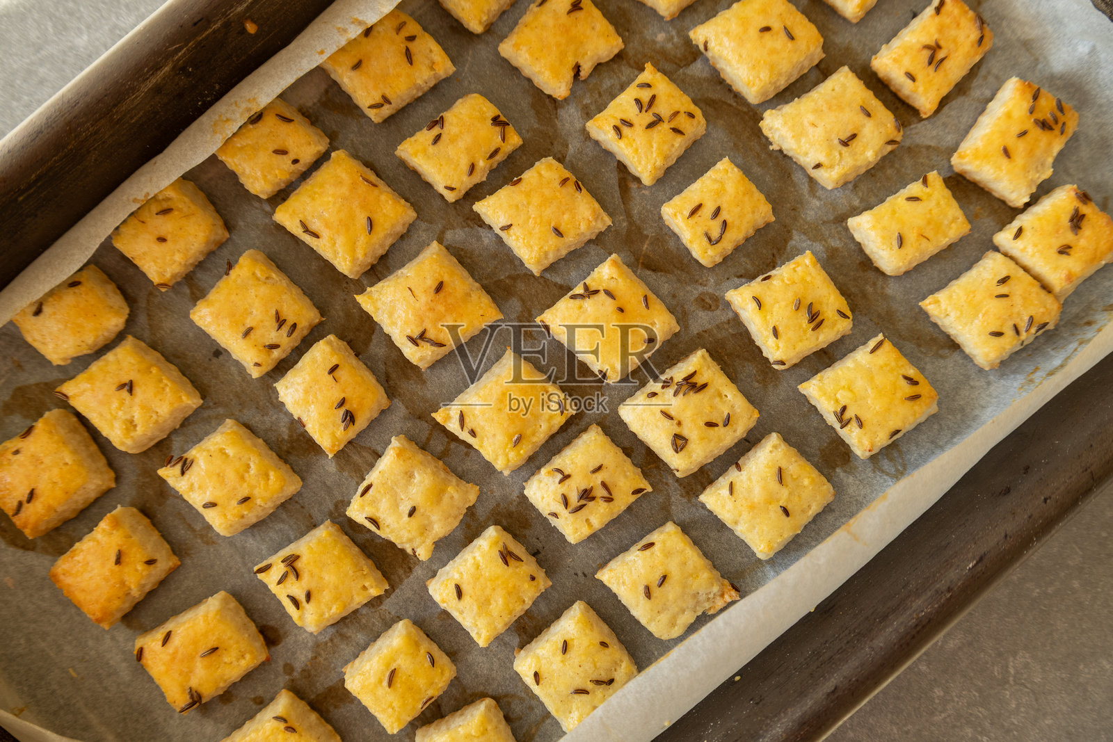 自制的茴香籽奶酪饼干放在烤盘上。照片摄影图片