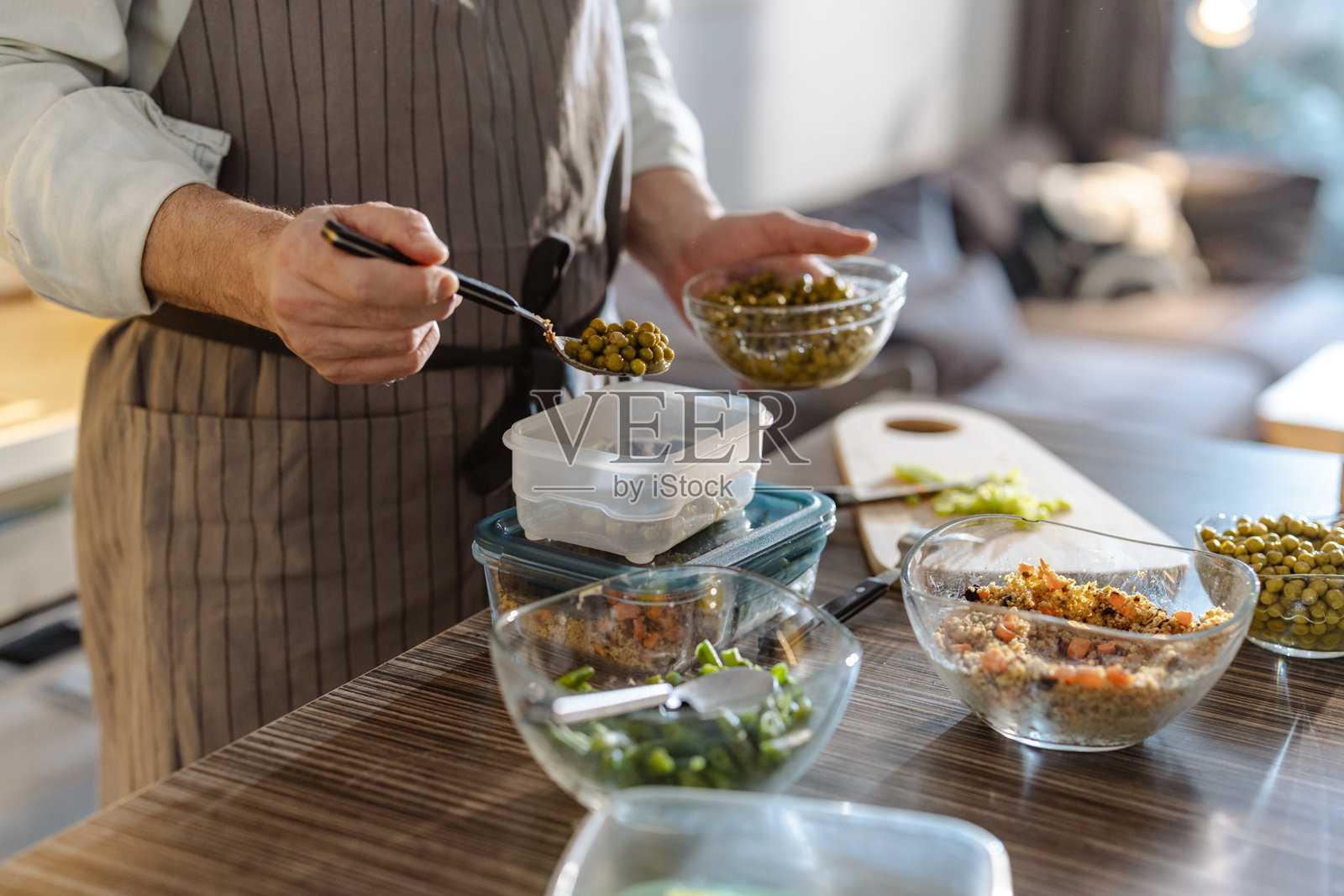 男子在厨房桌子上准备清晰容器中的蔬菜餐食照片摄影图片