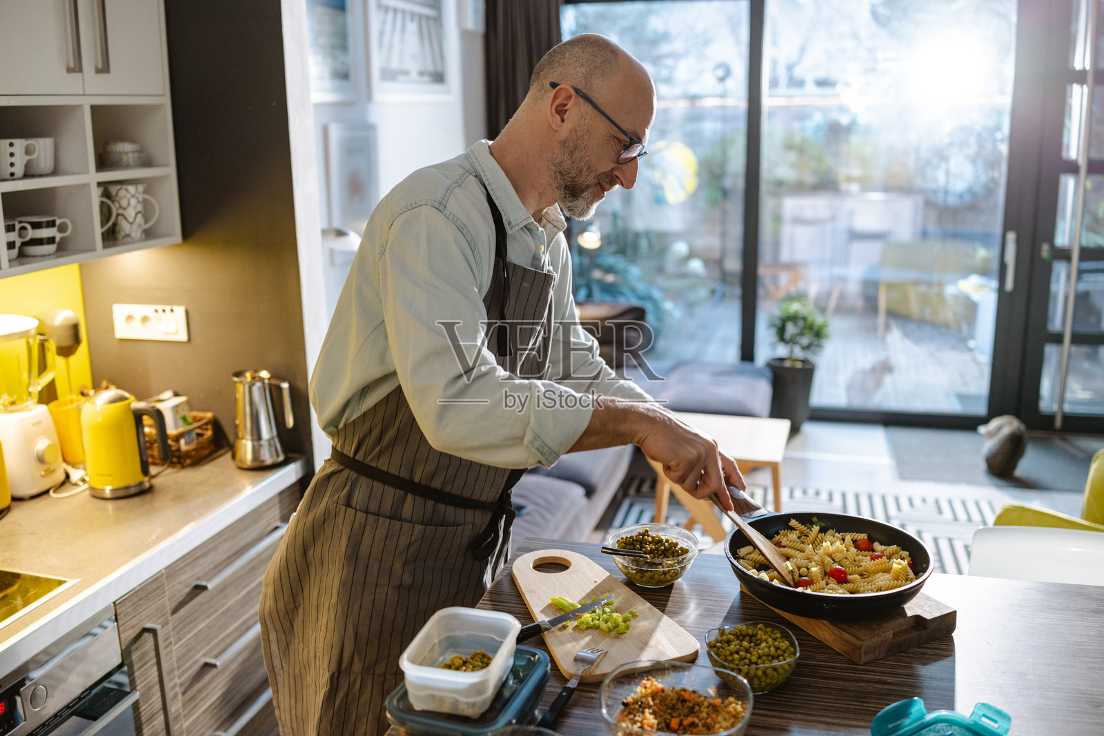 成熟男性在不粘锅中准备健康的意大利面餐。照片摄影图片