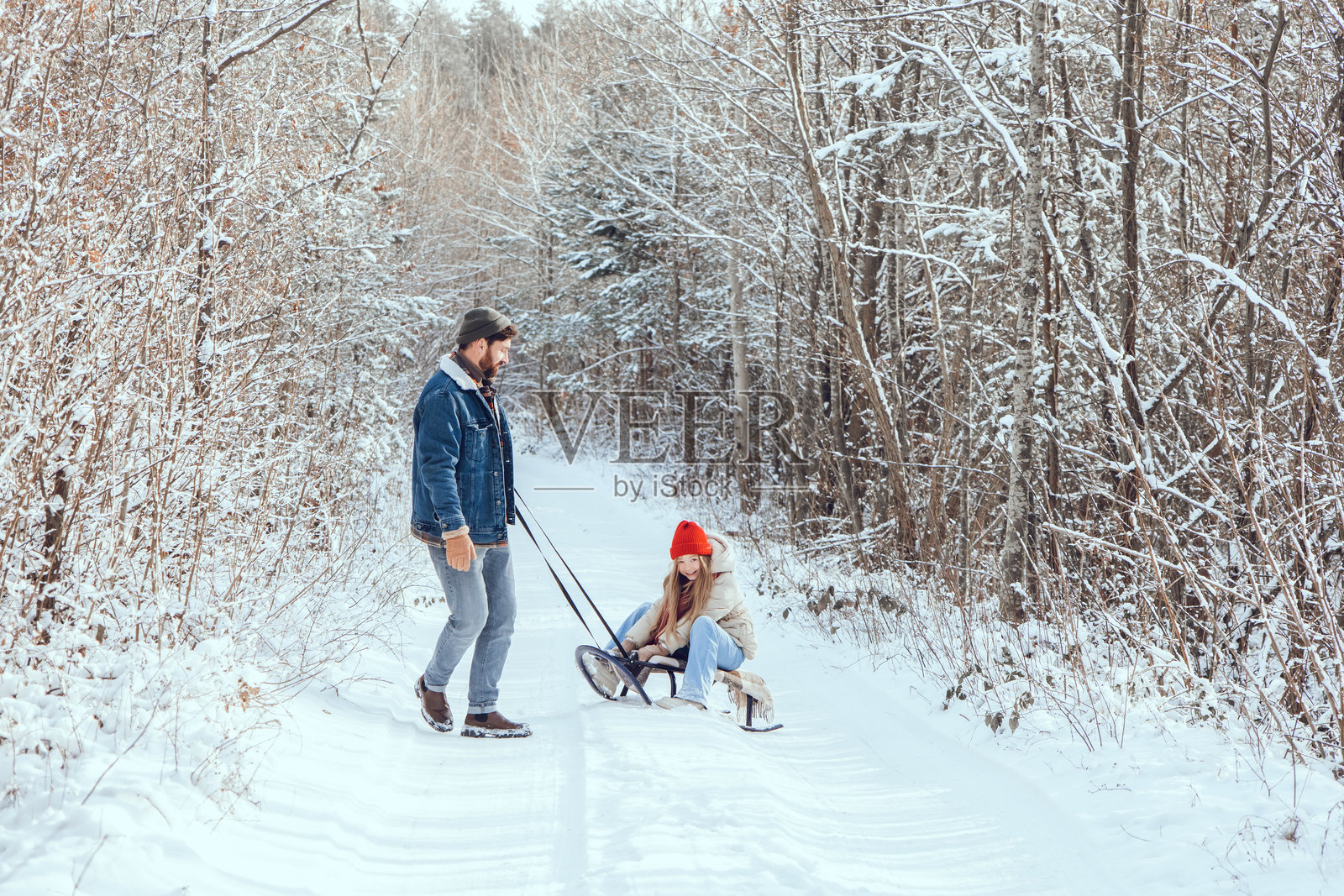 爸爸在冬季森林里拉着女儿的雪橇照片摄影图片