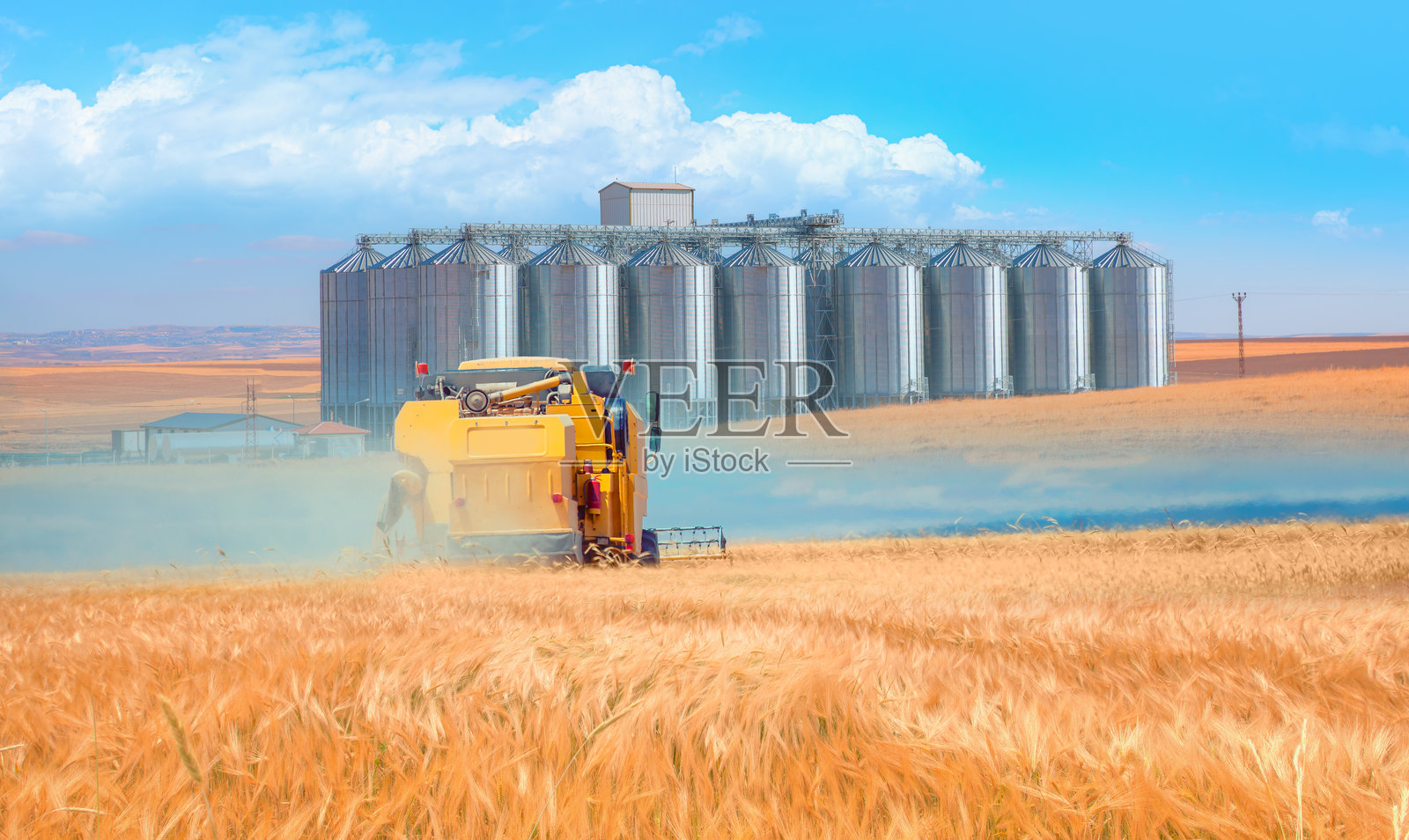 联合收割机在小麦田中收割 - 用于储存和干燥谷物的小型农业仓库，包括小麦、玉米、大豆和向日葵照片摄影图片