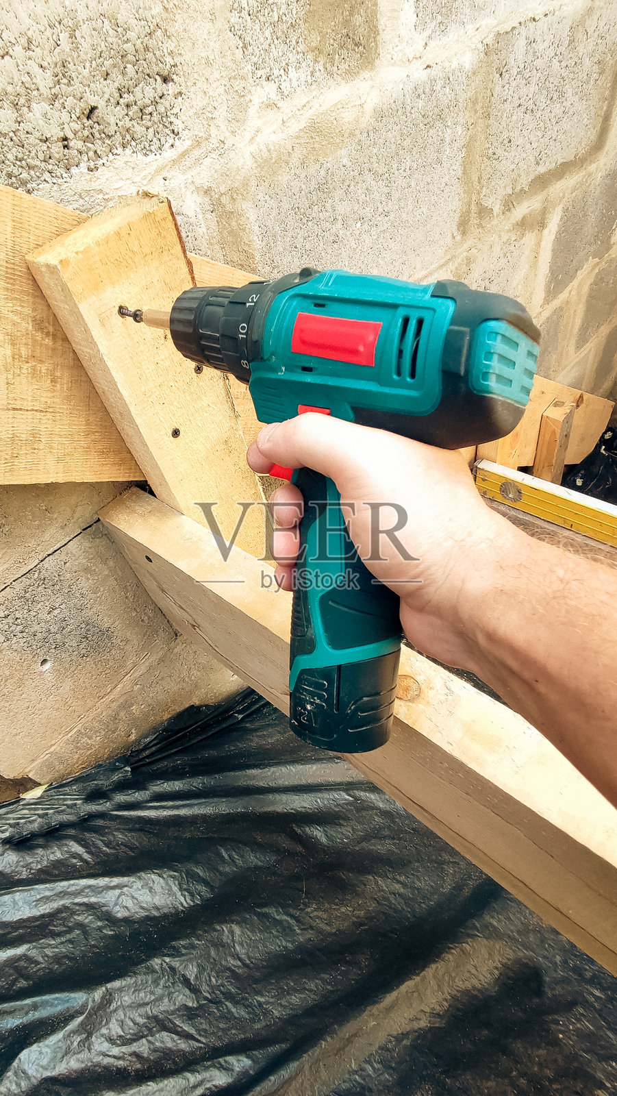 建筑工地上的电钻。工匠手中的螺丝刀特写。建筑概念。楼梯。楼梯结构。照片摄影图片