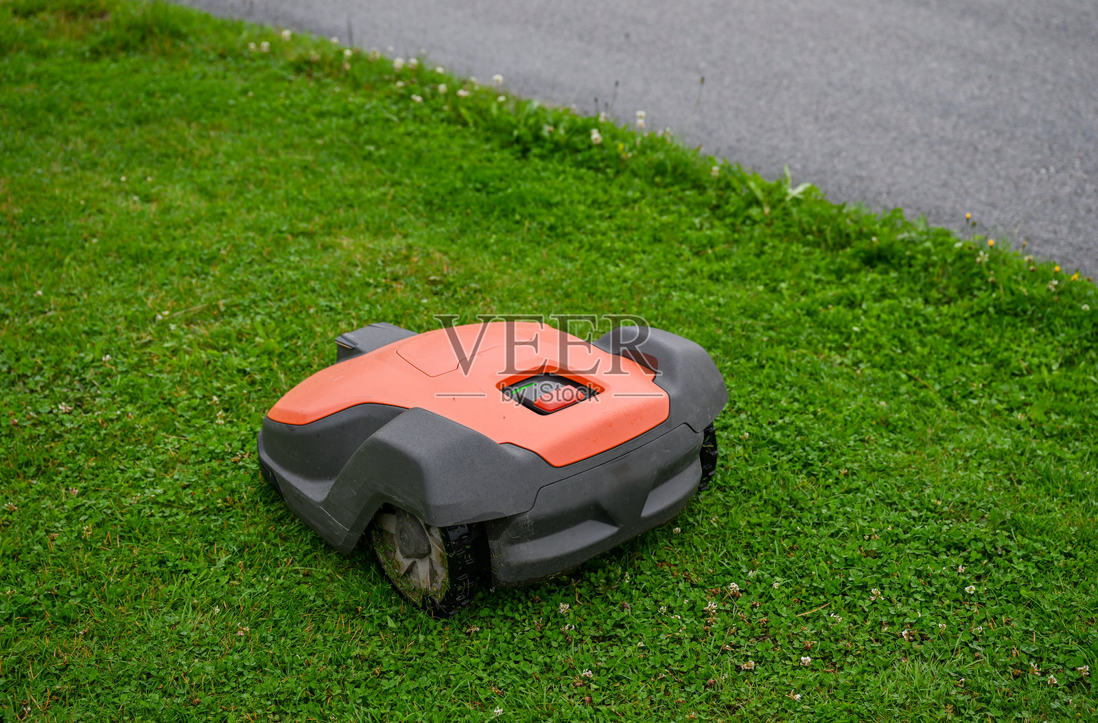 绿色草地上的机器人割草机，现代园艺的概念照片摄影图片