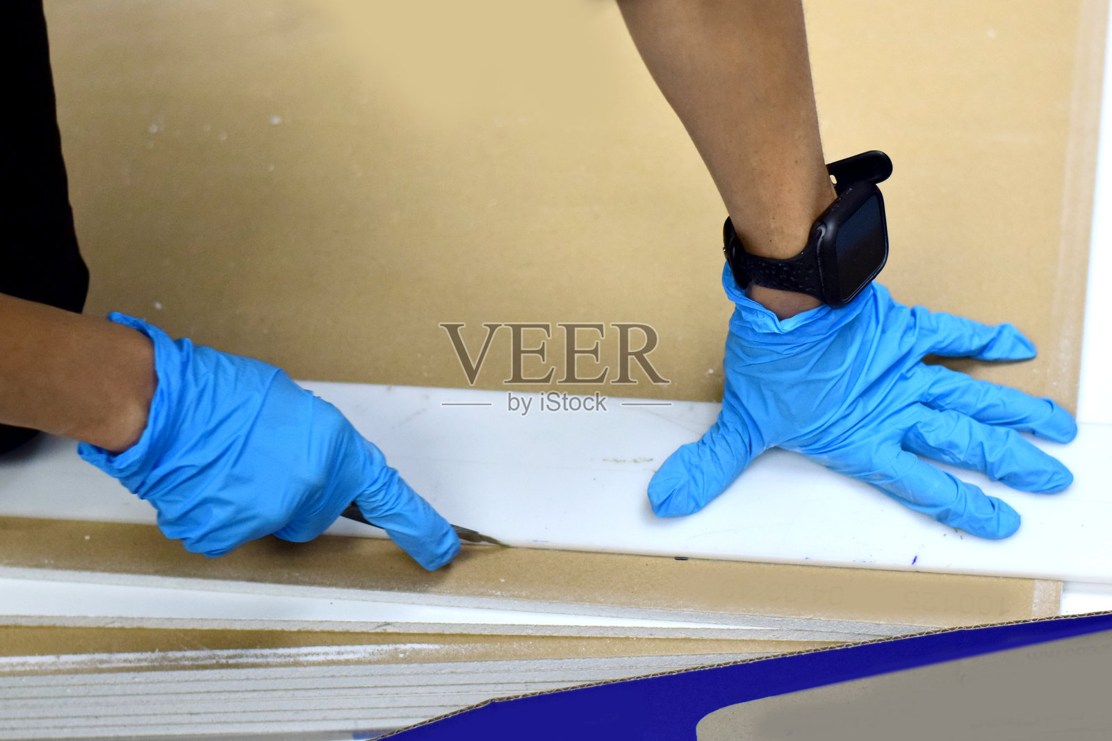 一名天花板技术人员正在使用刀片切割天花板以进行修理和更换。照片摄影图片