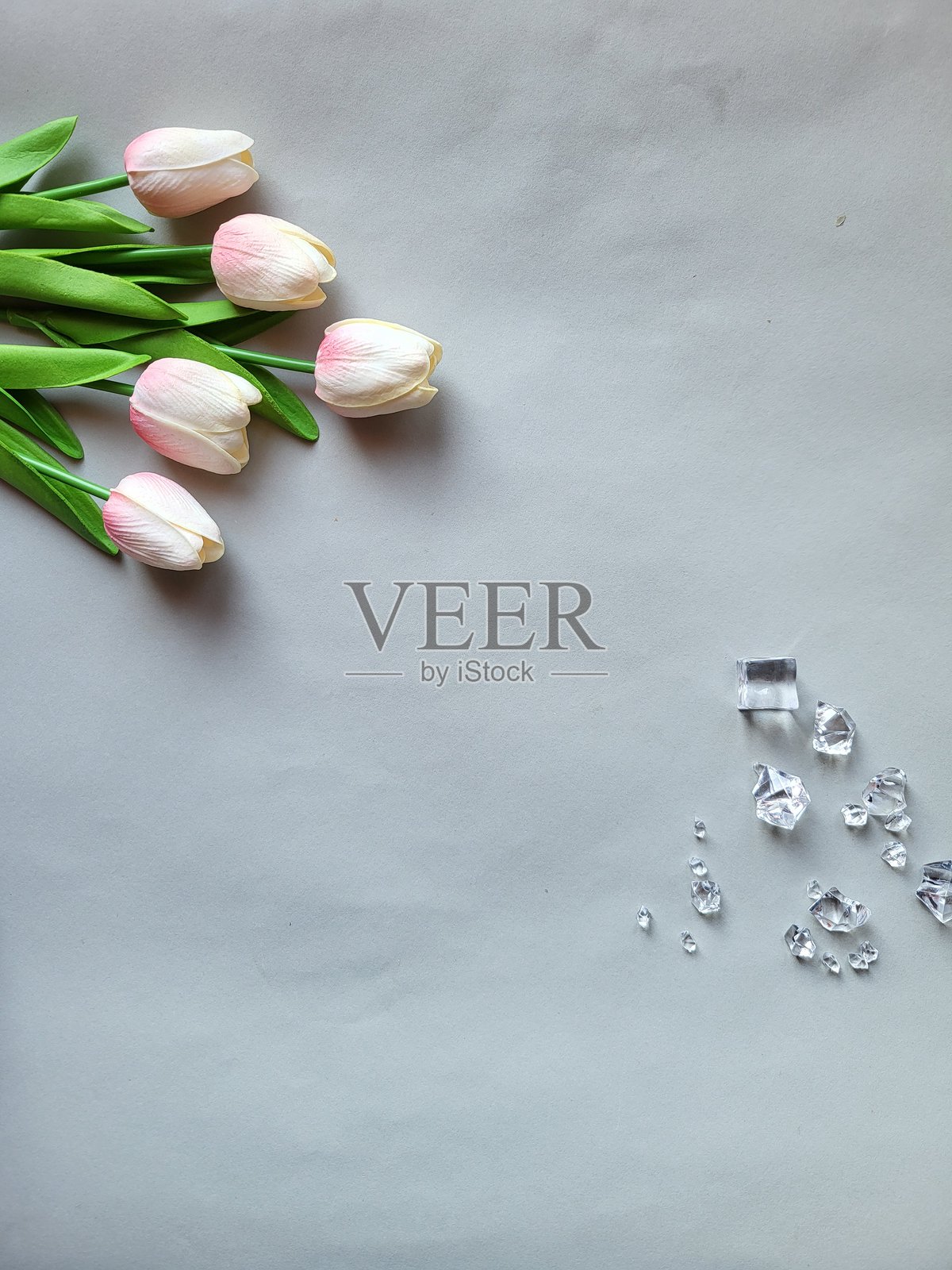 灰色背景上的粉色郁金香和透明水晶照片摄影图片