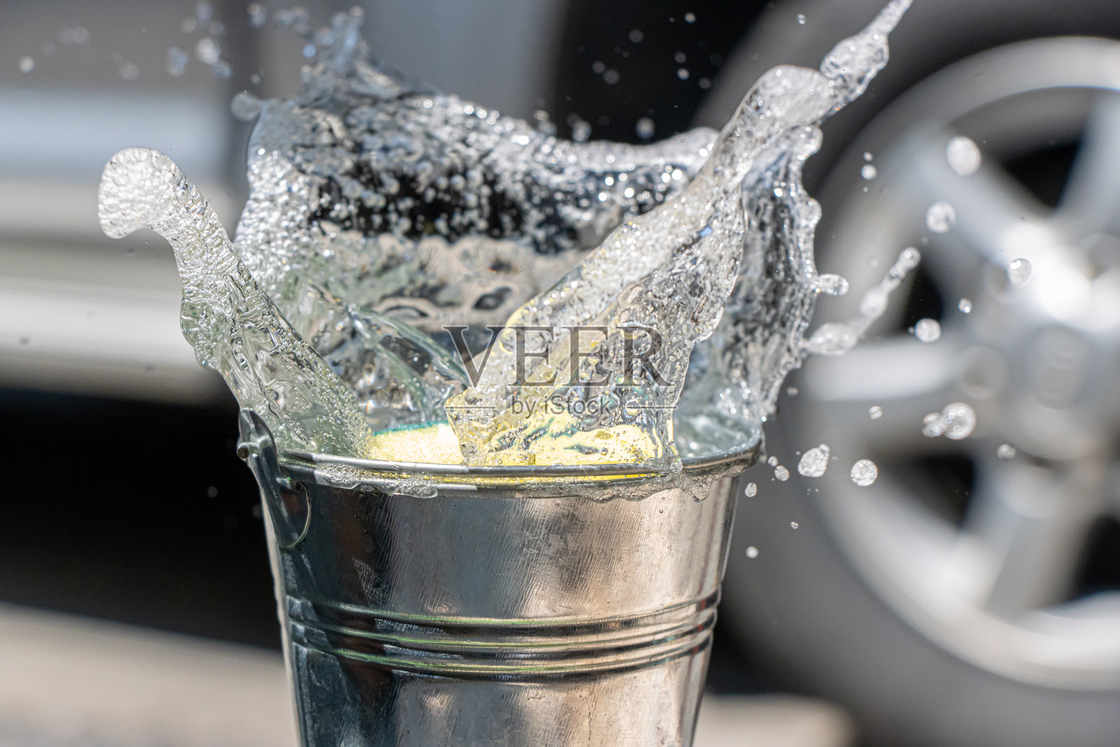 海绵掉入装有洗涤剂的水桶中。用肥皂水手洗汽车。照片摄影图片